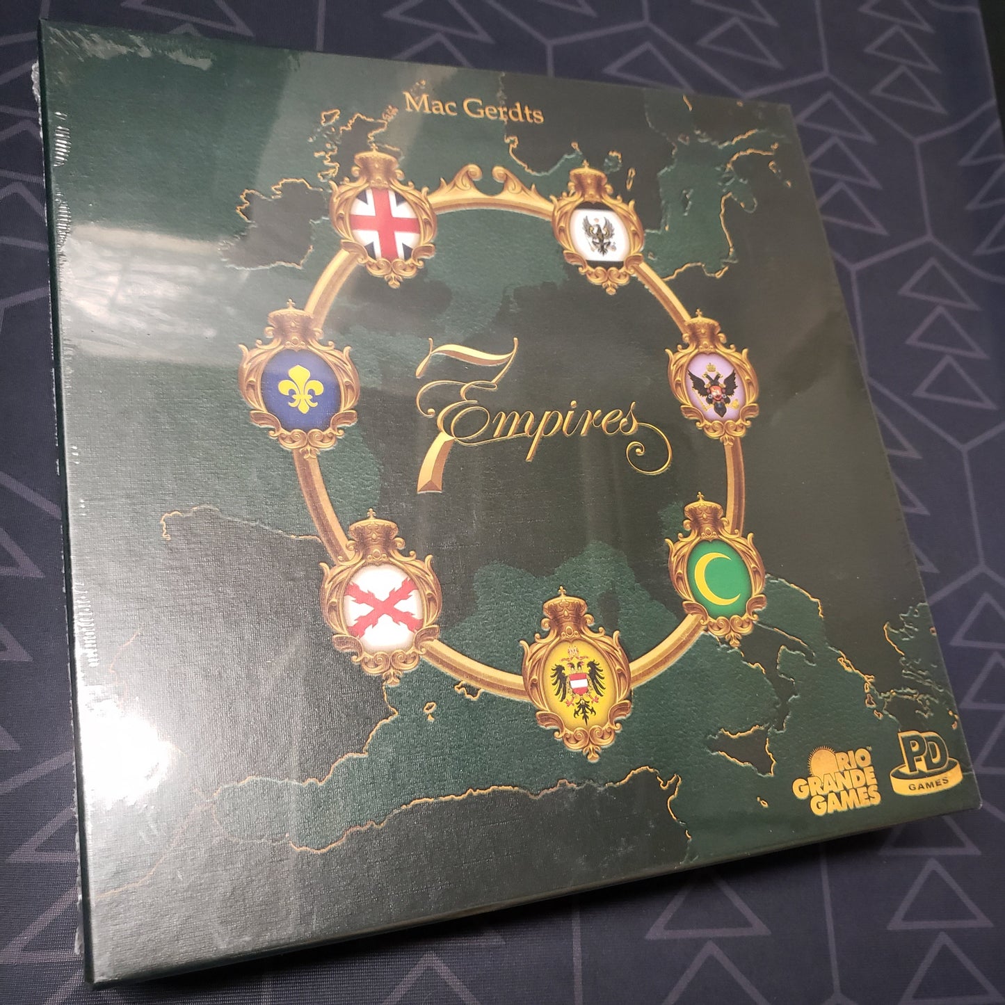 Image shows the front cover of the box for the 7 Empires board game