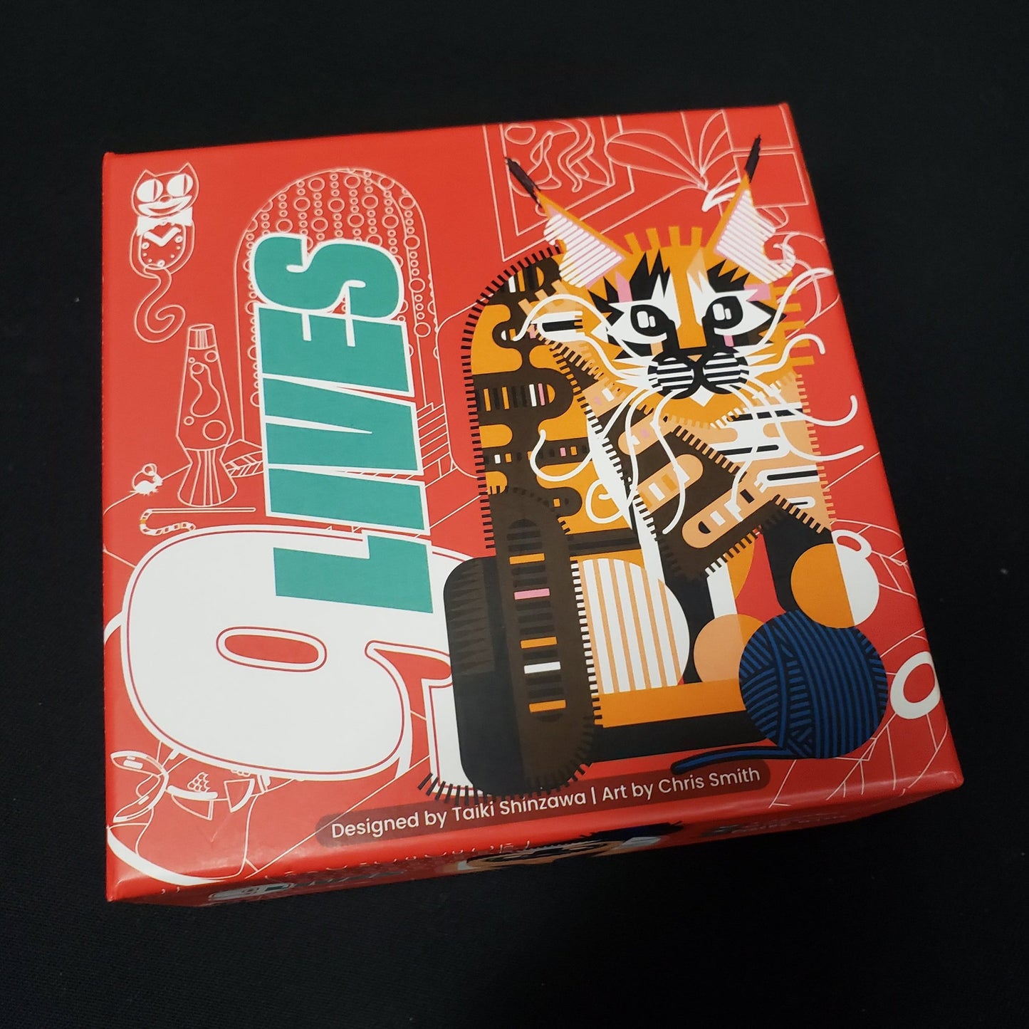 Image shows the front cover of the box of the 9 Lives card game