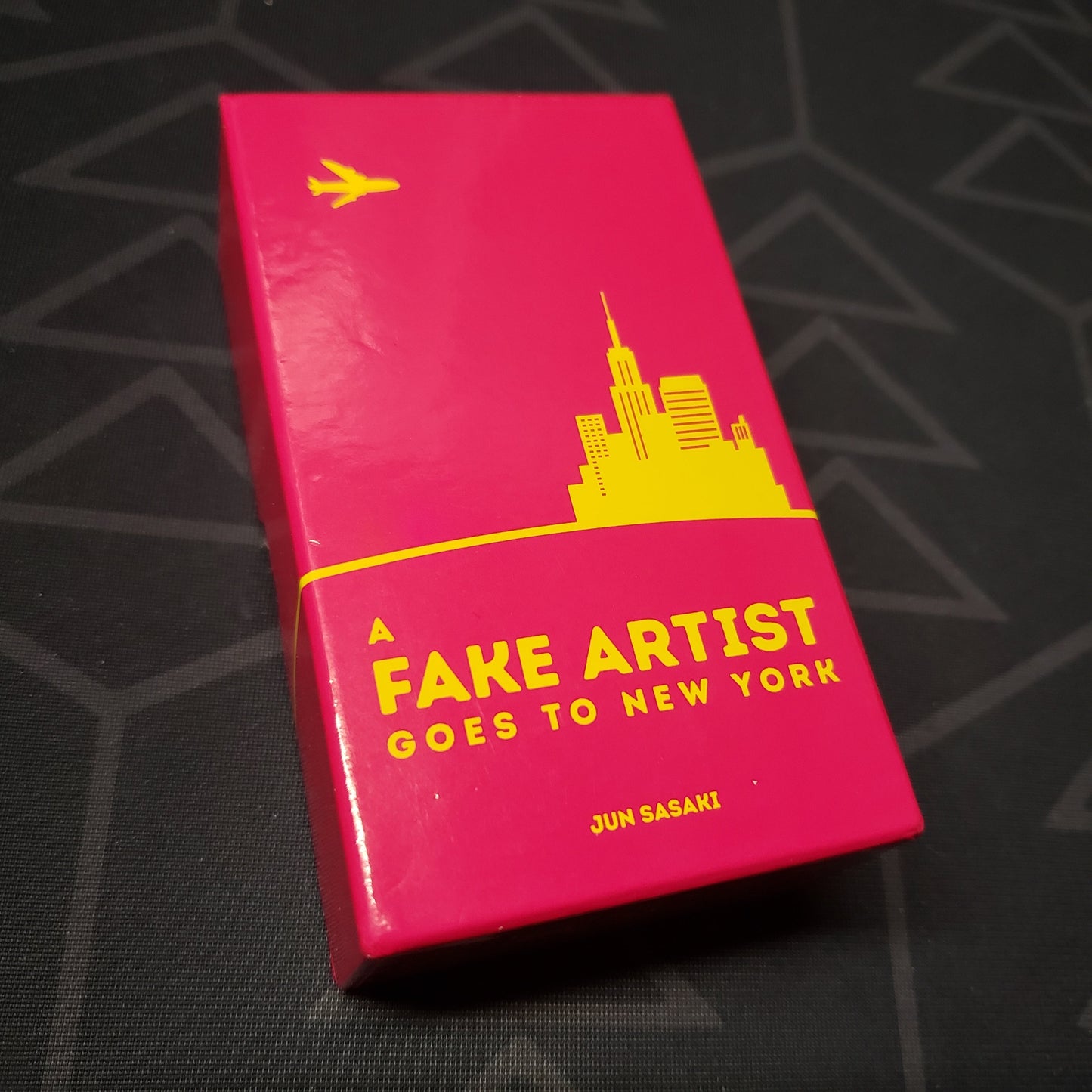 Image shows the front cover of the box of the board game A Fake Artist Goes to New York