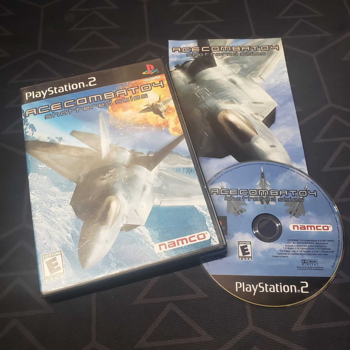 Image shows the case, manual and disc for the video game Ace Combat 4: Shattered Skies for Playstation 2