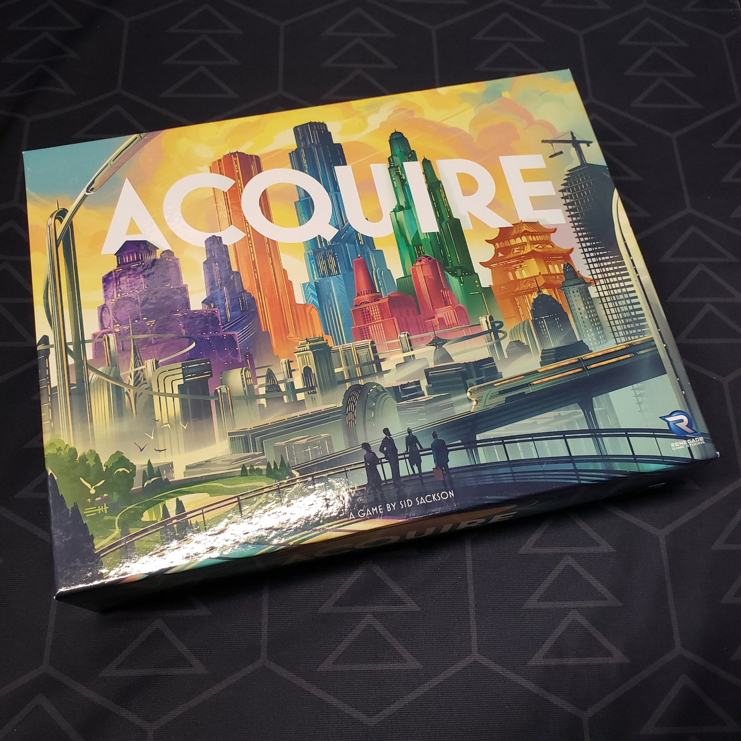 Image shows the updated front cover art of the box of the Acquire: 2023 Edition board game
