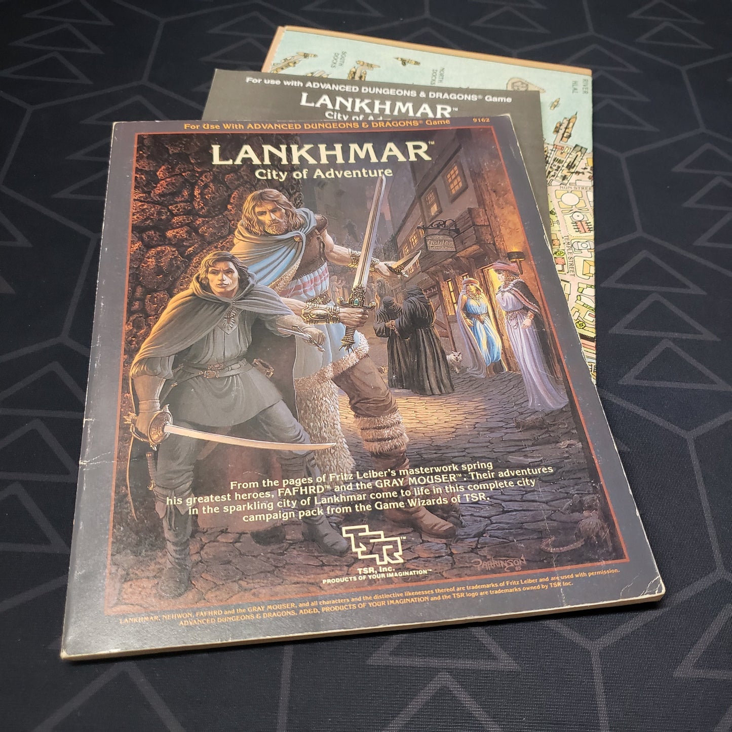 Image shows the front cover of the folio for the Lankhmar, City of Adventure module for the roleplaying game Advanced Dungeons & Dragons: First Edition, with the booklet and map inserts fanned out