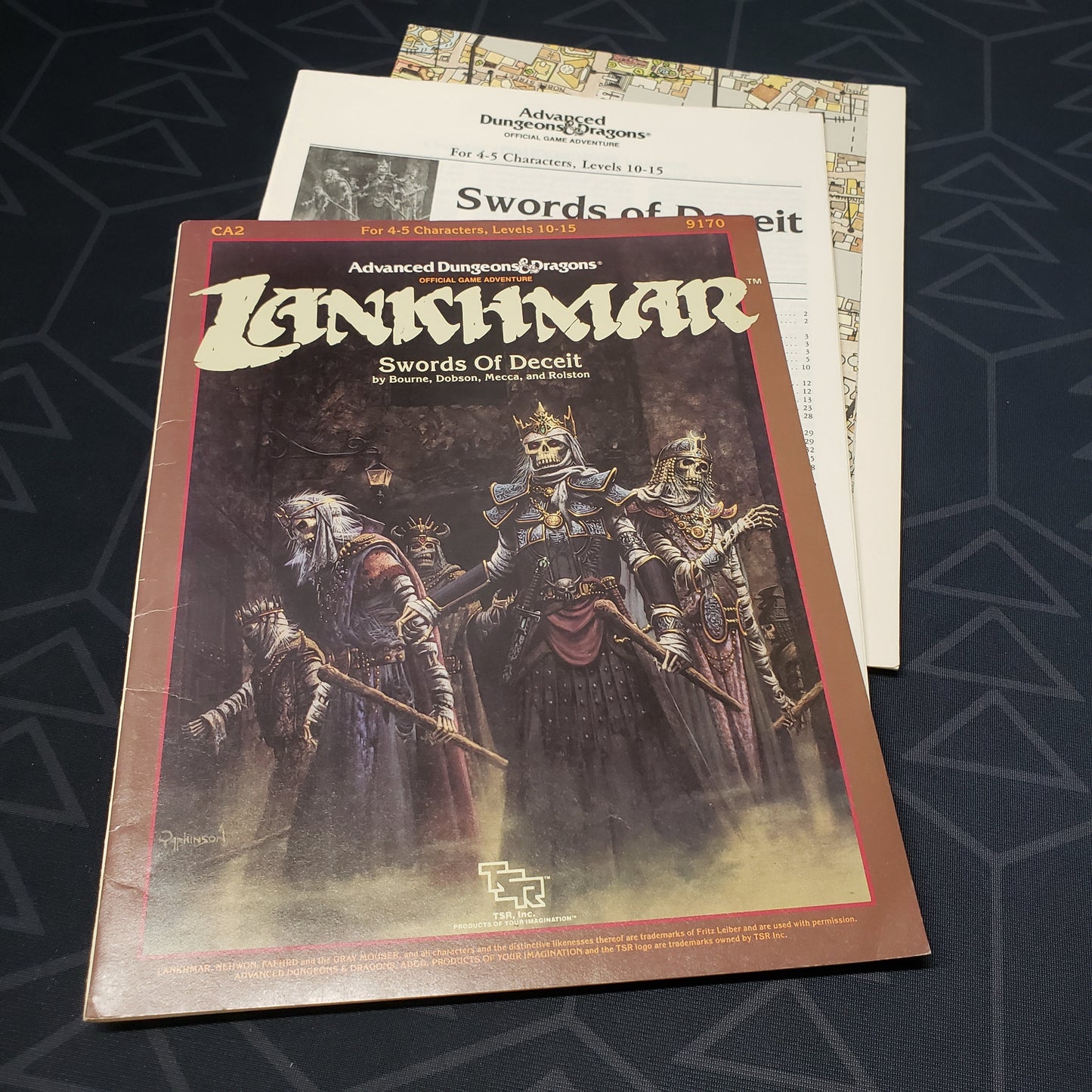 Image shows the front cover of the folio for the Swords of Deceit adventure module for the roleplaying game Advanced Dungeons & Dragons: First Edition, with the booklet and map inserts fanned out