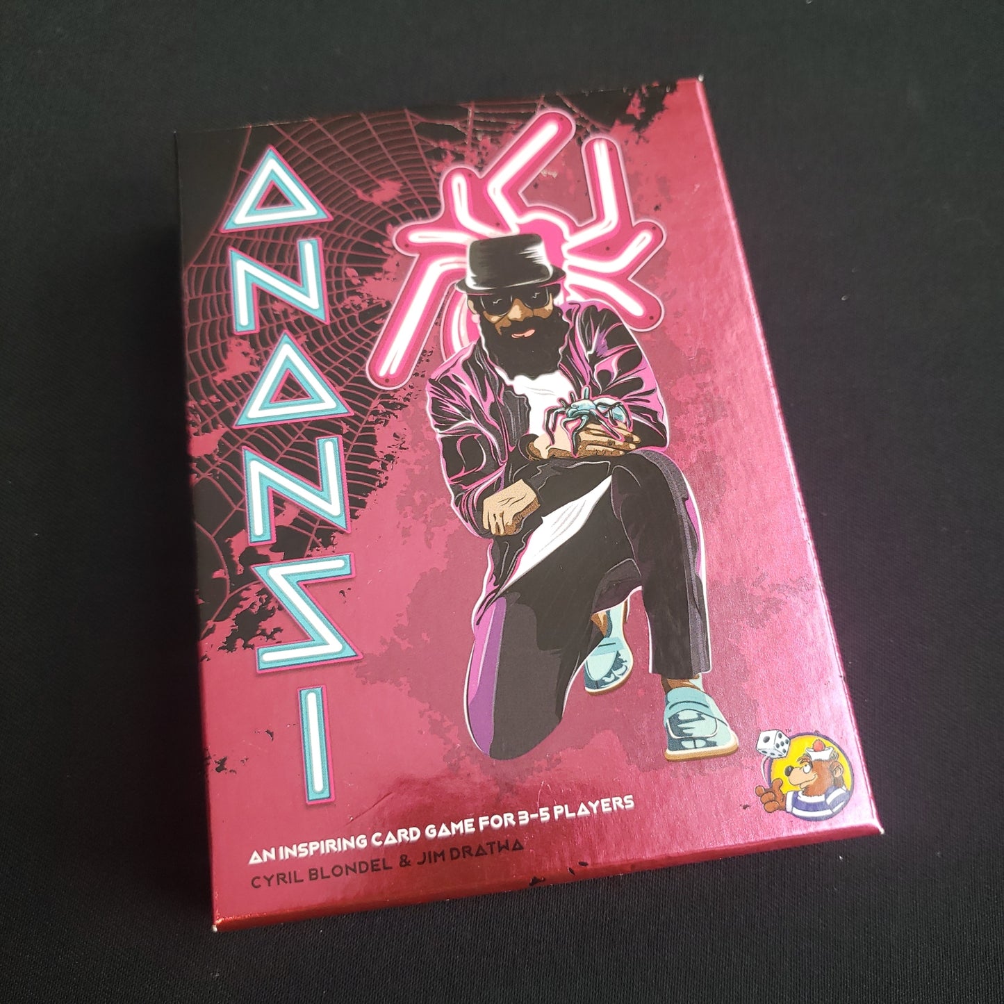 Image shows the front cover of the box of the Anansi card game