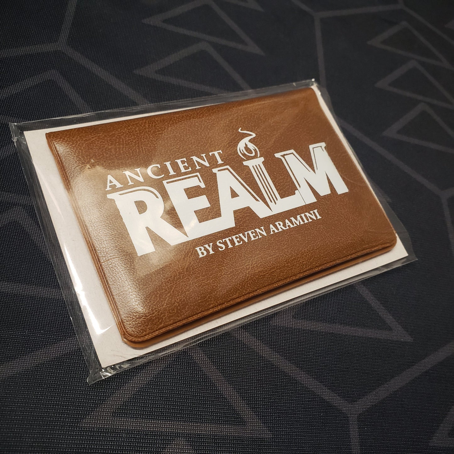 Image shows the front cover of the card wallet packaging of the Ancient Realm card game