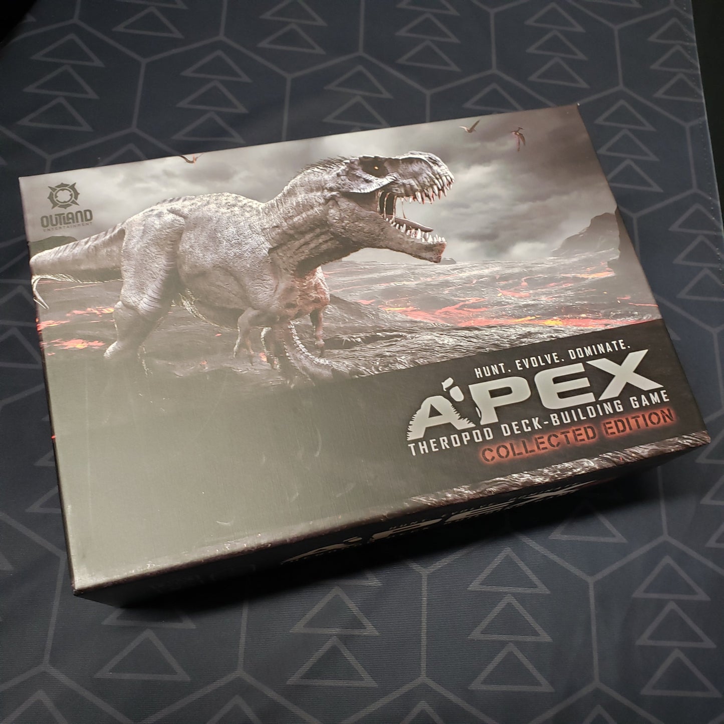 Image shows the front cover of the box for the Apex Theropod Deck-Building Game (Collected Edition) card game