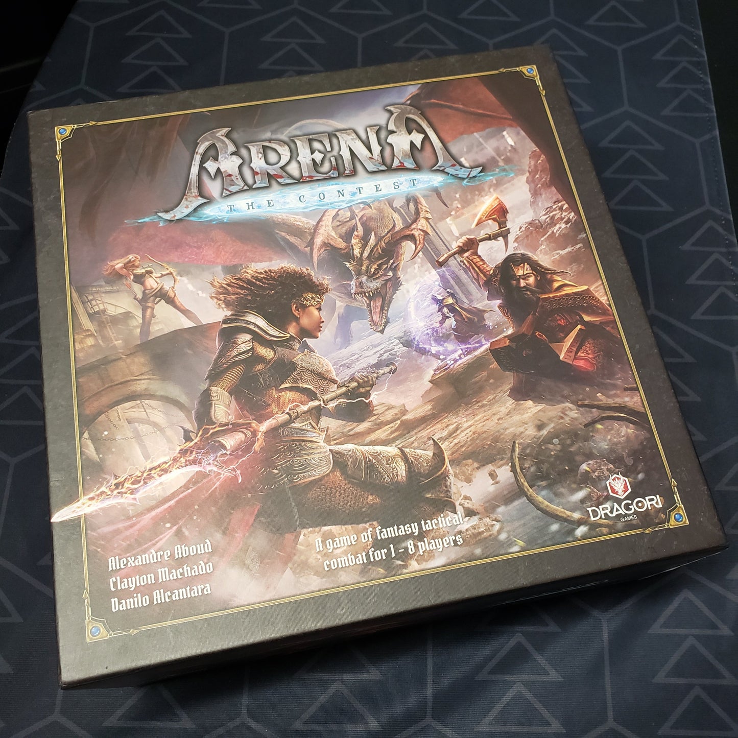 Image shows the front cover of the box of the board game Arena: The Contest