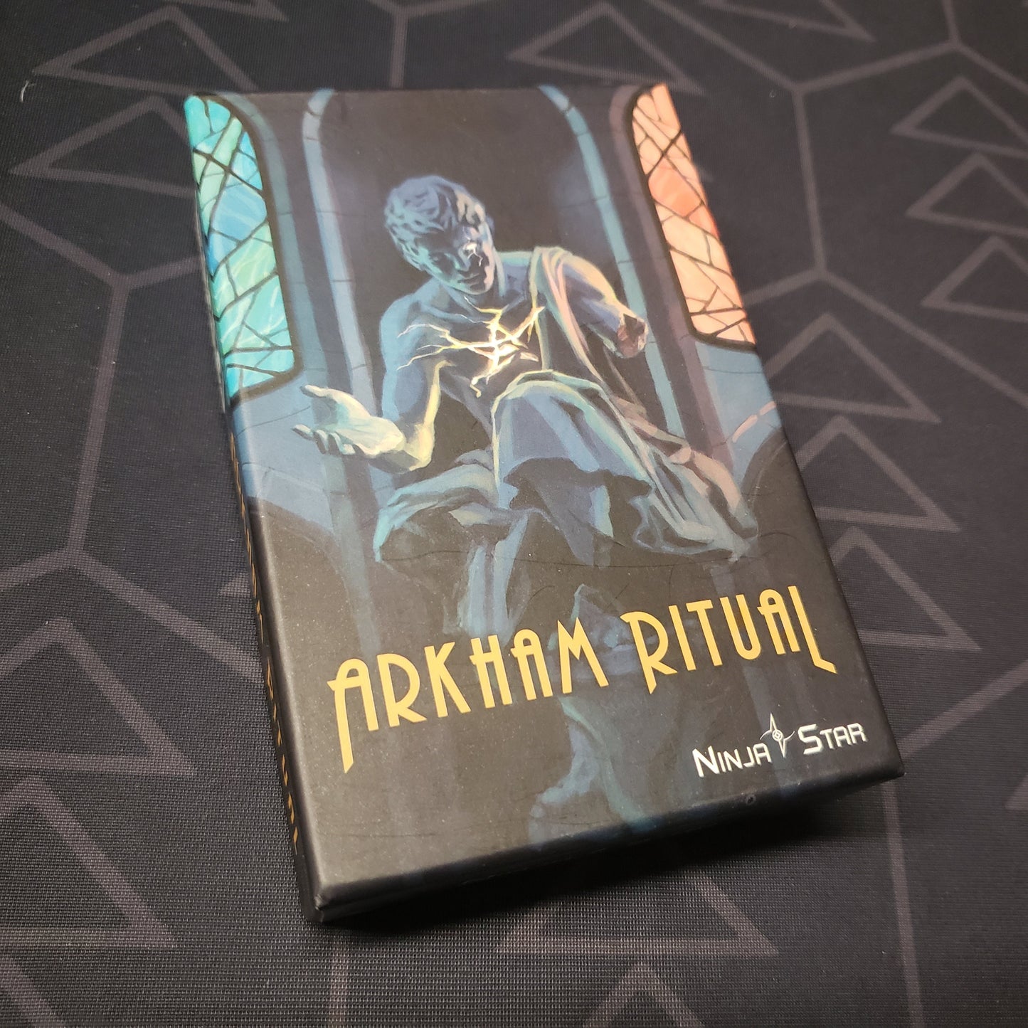 Image shows the front cover of the box of the Arkham Ritual card game