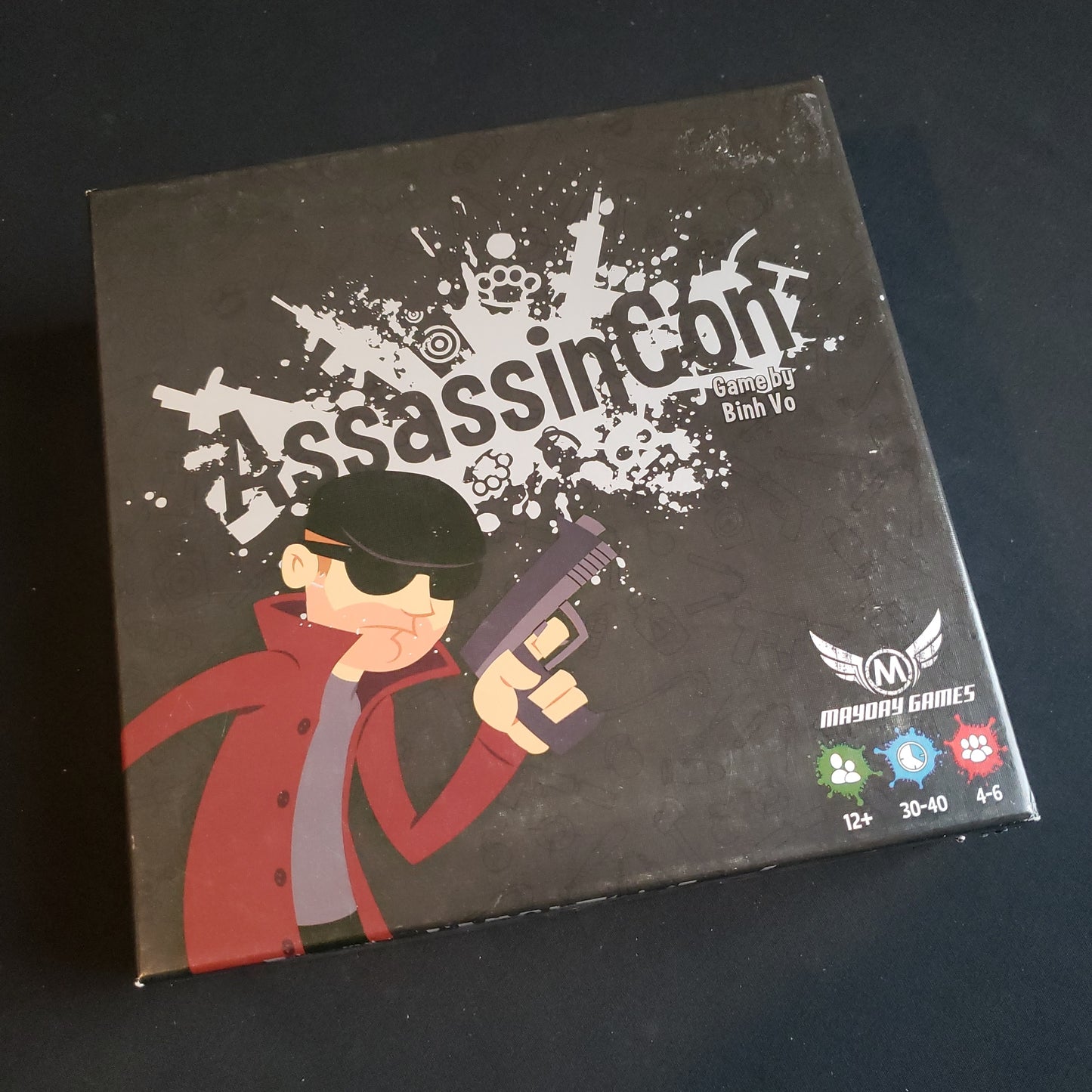 Image shows the front cover of the box of the AssassinCon board game