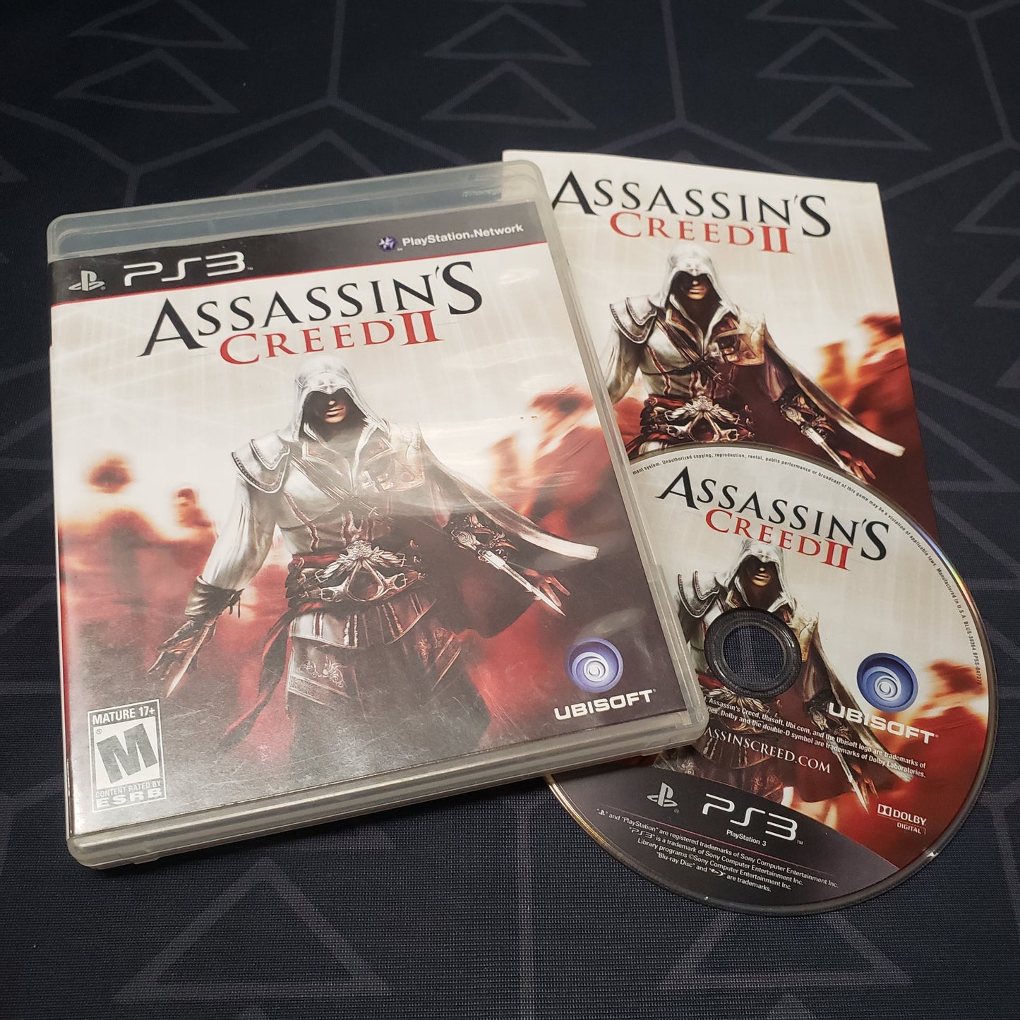 Image shows the case, manual and disc for the video game Assassin's Creed II for Playstation 3