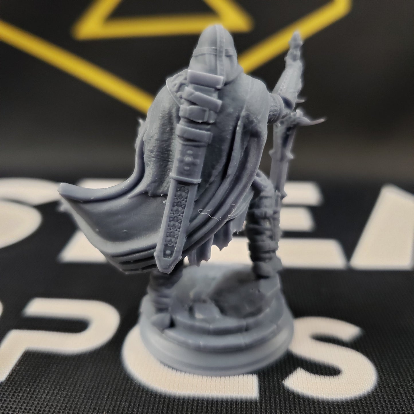 Image shows the back of a 3D printed undead ranger gaming miniature, holding a large sword in one hand and conjuring a spell with the other