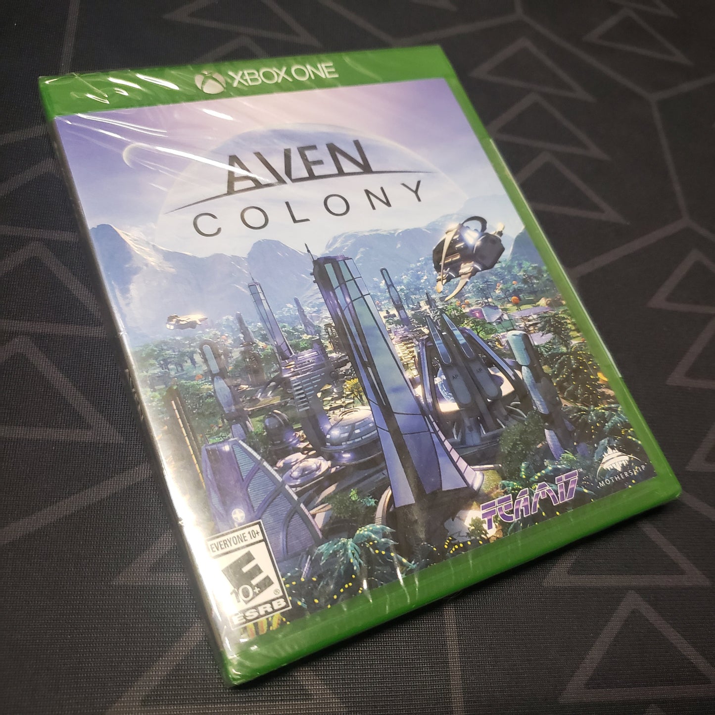 Image shows the front of the case for the video game Aven Colony for Xbox One