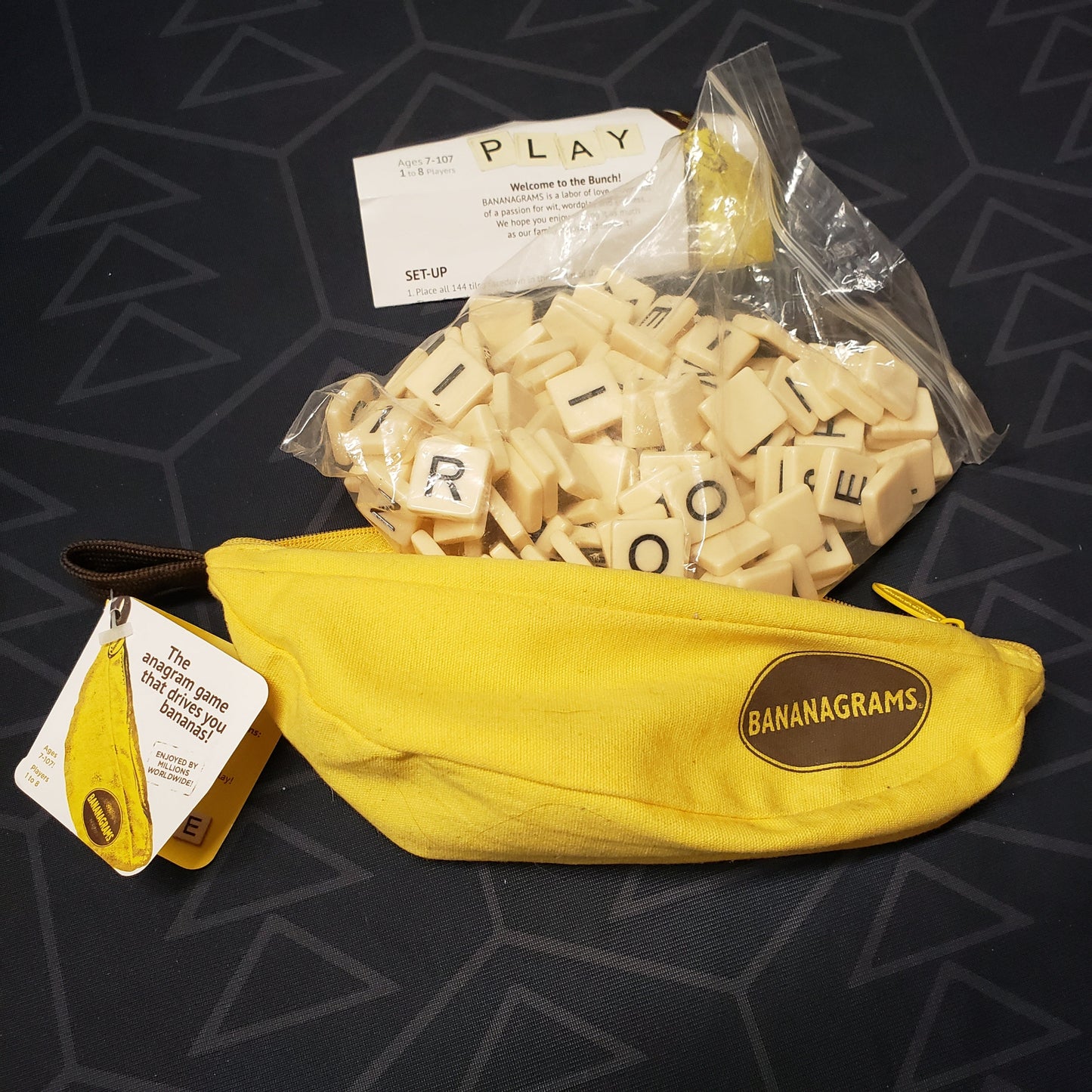 Image shows the banana-shaped pouch for the Bananagrams board game with the bagged letter tiles spilling out of it