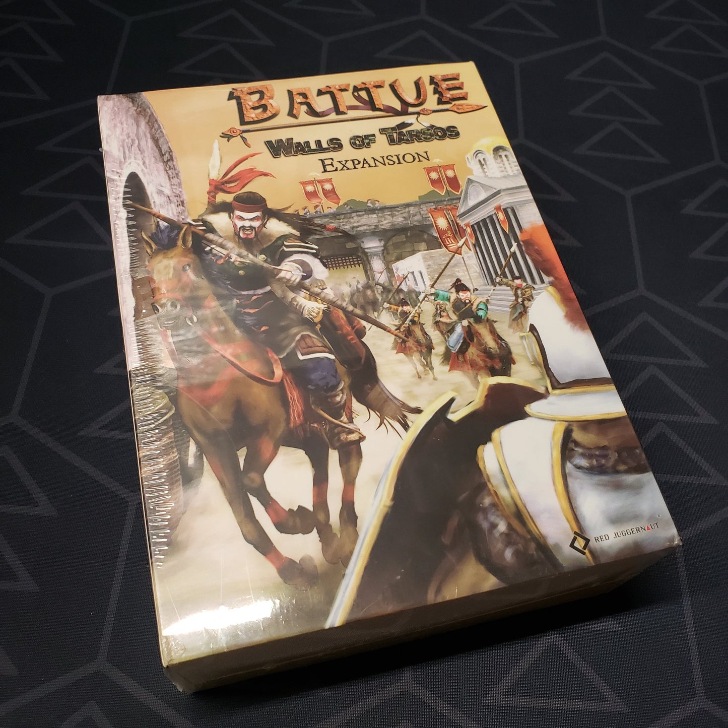 Image shows the front cover of the box of the Walls of Tarsos expansion for the board game Battue