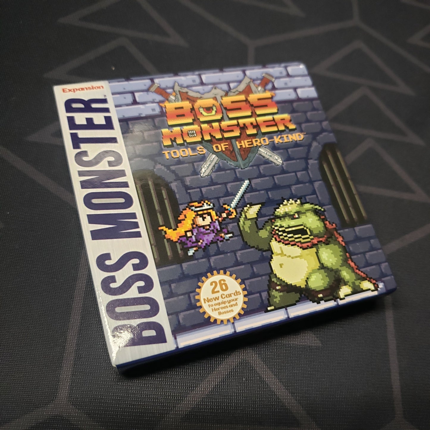 Image shows the front cover of the Tools of Hero Kind expansion for the card game Boss Monster