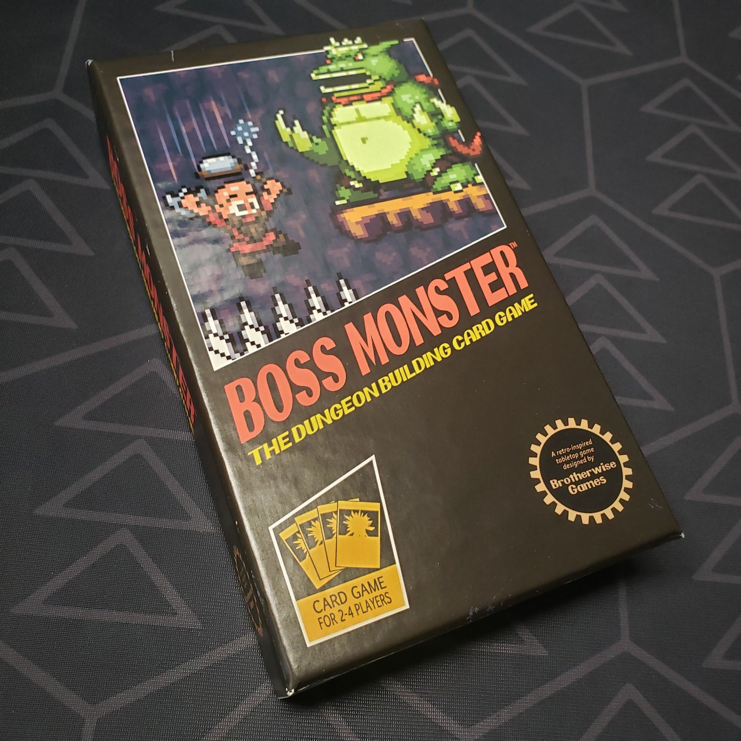 Image shows the front cover of the box of the Boss Monster card game