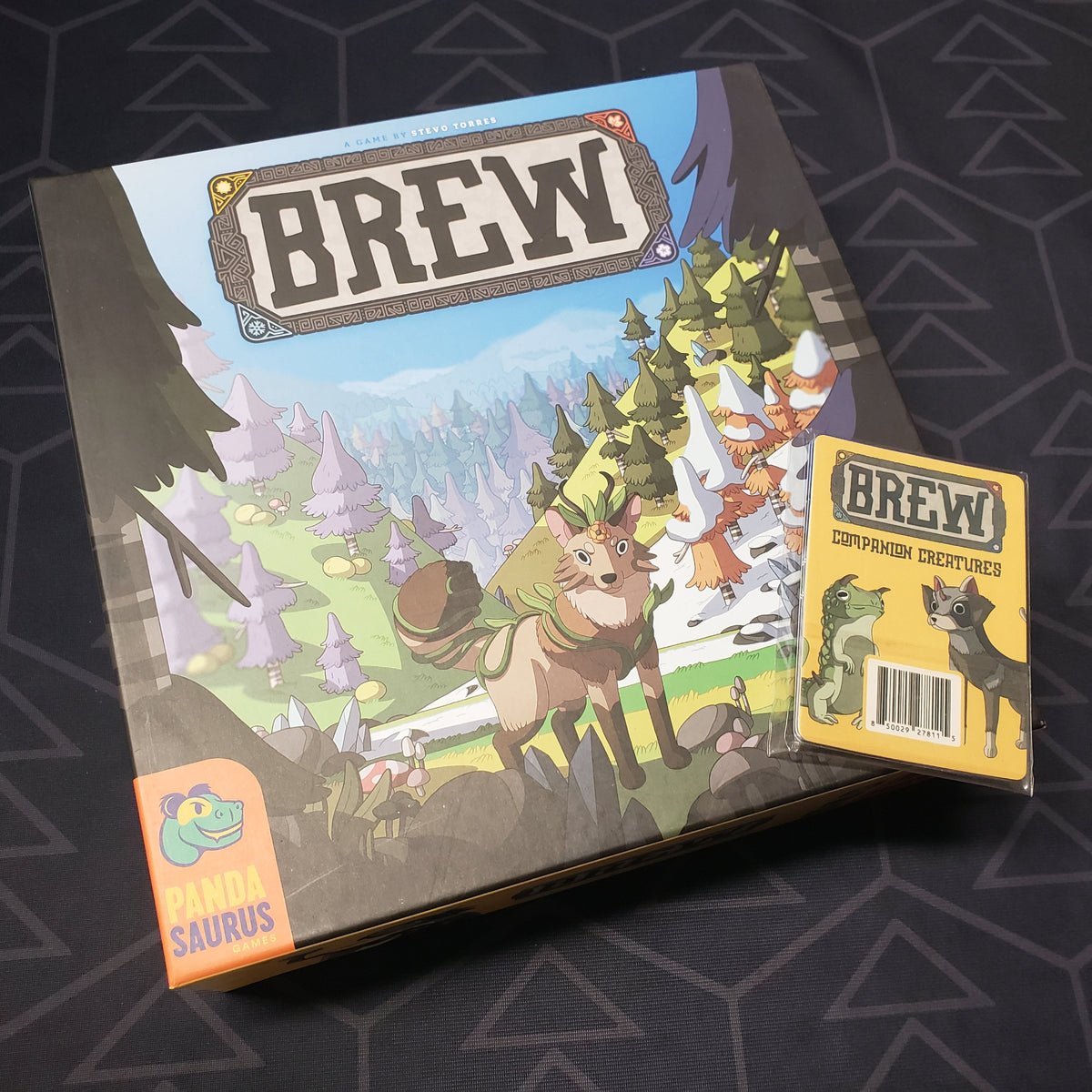 Image shows the front cover of the box of the Brew board game with the Companion Creatures mini expansion sitting on top of it