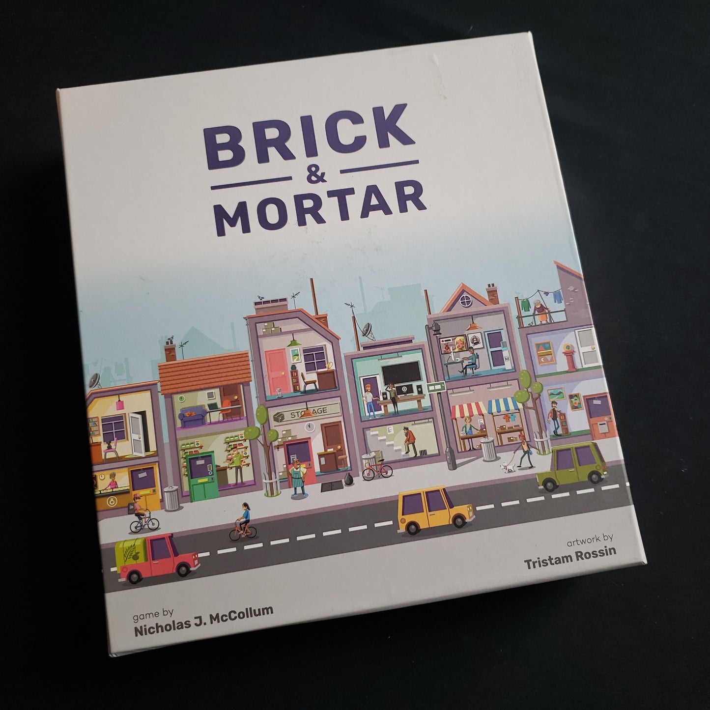 Image shows the front cover of the box of the Brick & Mortar board game