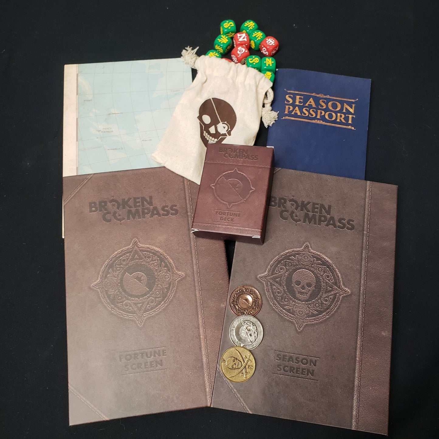 Image shows the Fourtune Master's screen and multiple accessories for the roleplaying game Broken Compass