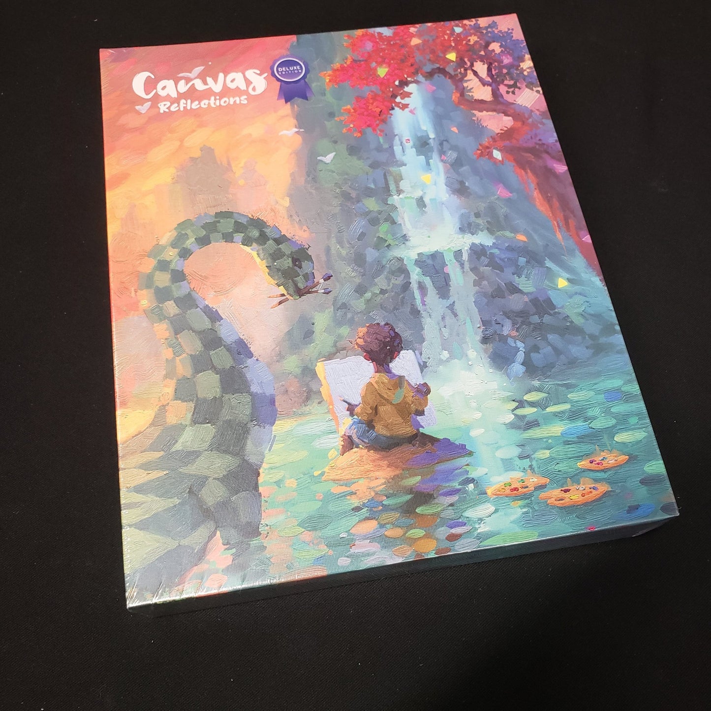 Image shows the front cover of the box of the Reflections expansion for the board game Canvas