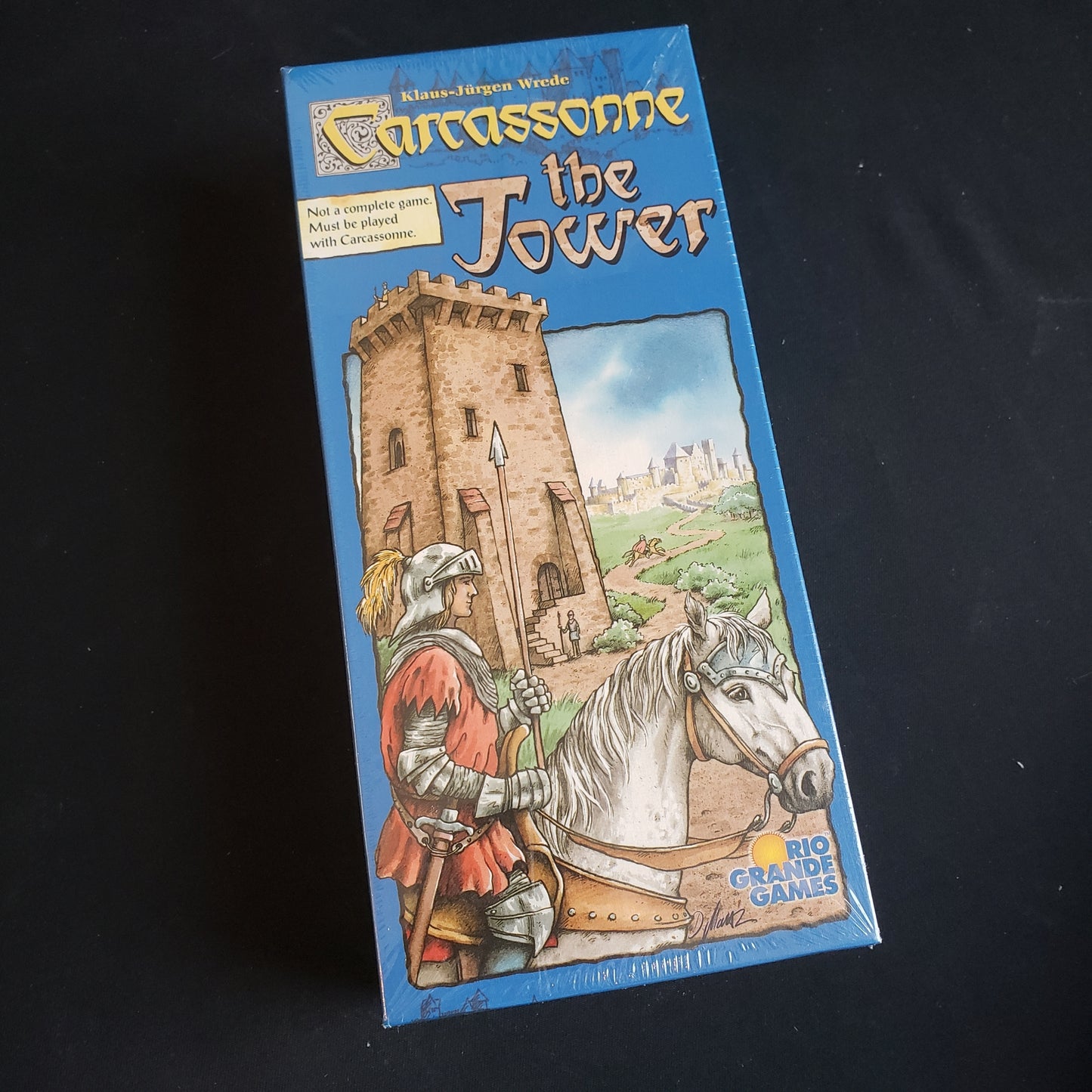 Image shows the front cover of the box of the Tower expansion for the board game Carcassonne