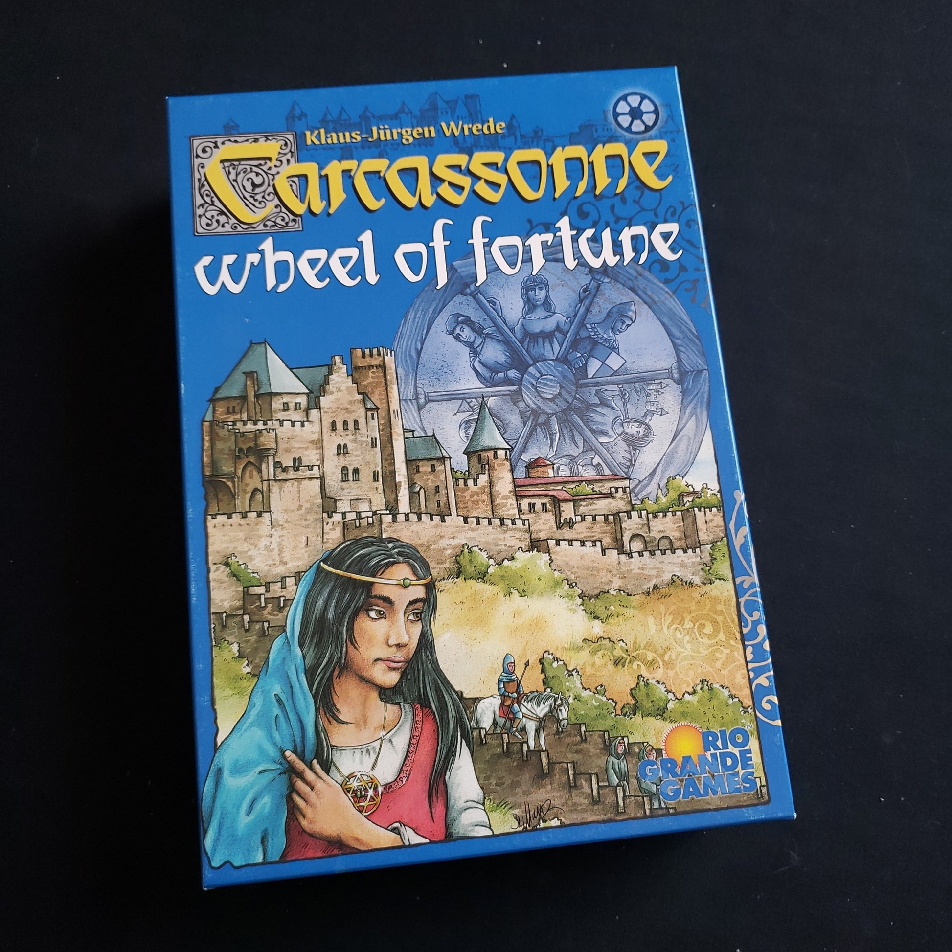 Image shows the front cover of the box of the Carcassonne: Wheel Of Fortune board game