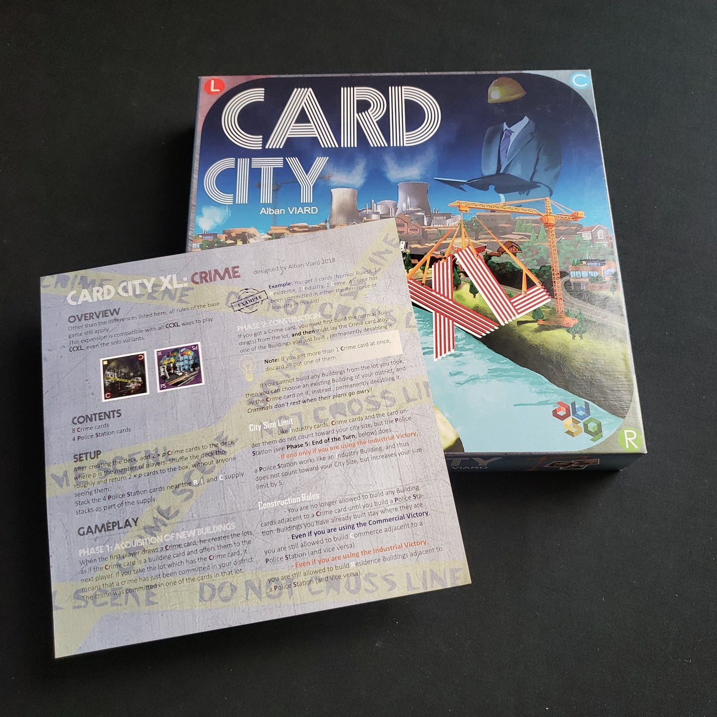 Image shows the front cover of the box of the Card City XL board game with the instructions for the Crime expansion sitting on top of it.