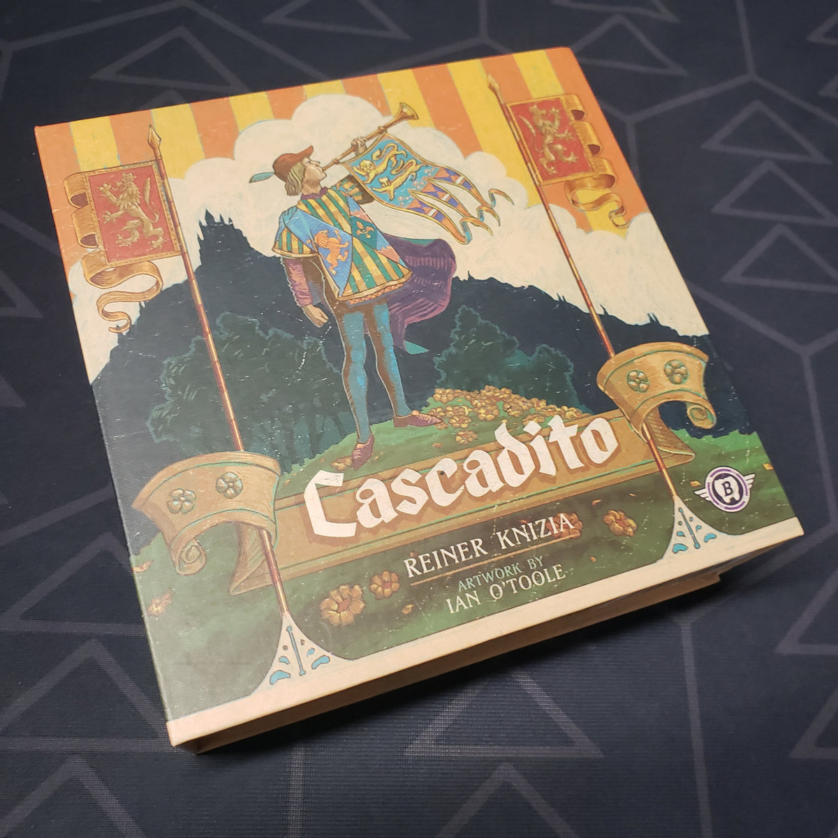 Image shows the front cover of the box of the Cascadito board game