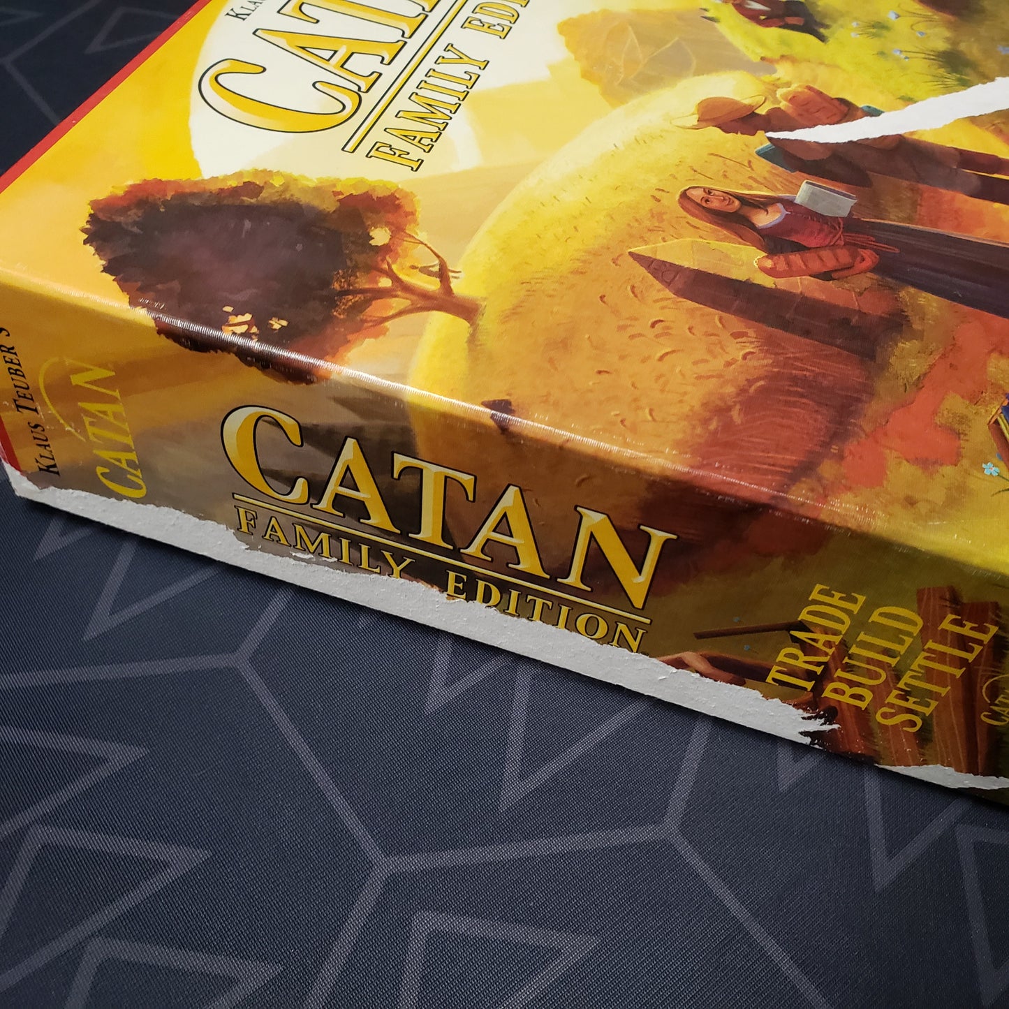 Image shows the some tape damage along the side of the box for the Catan: Family Edition board game