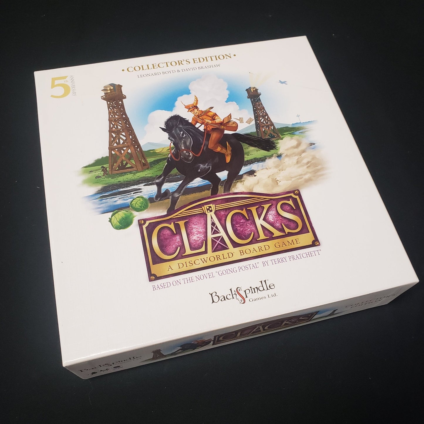 Image shows the front cover of the box of the Clacks board game