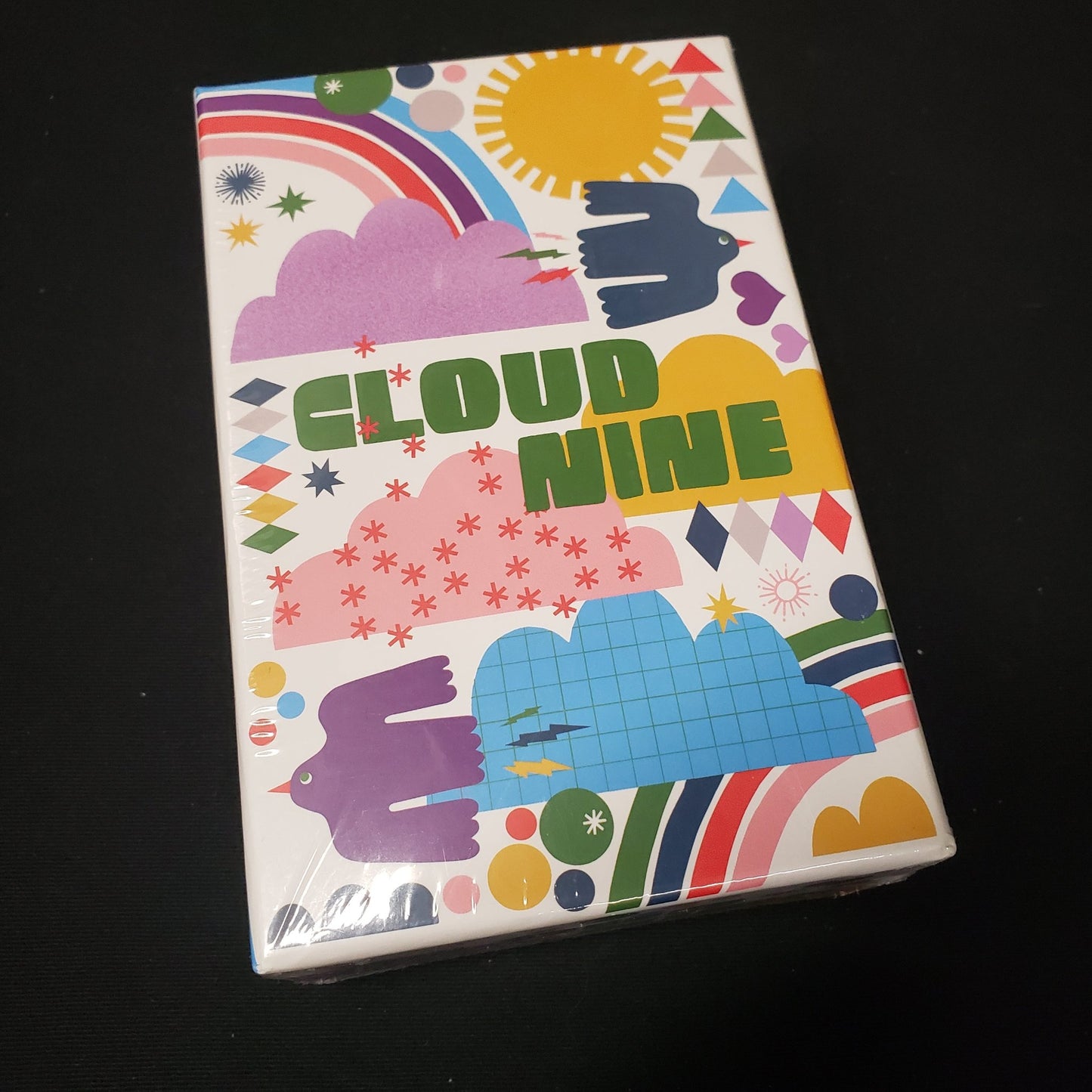 Image shows the front cover of the box of the Cloud Nine card game