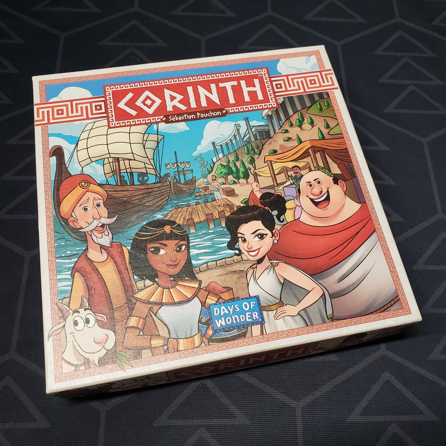 Image shows the front cover of the box of the Corinth board game