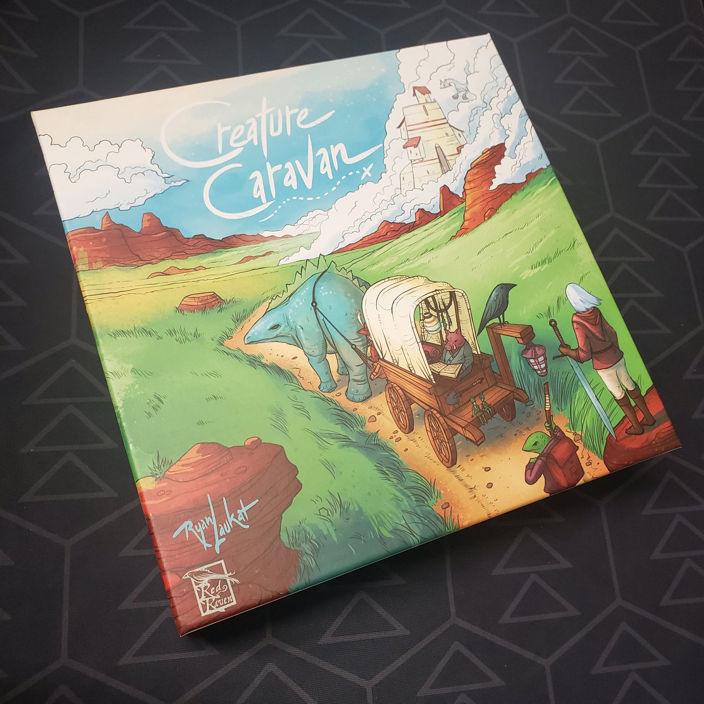 Image shows the front cover of the box of the Creature Caravan board game