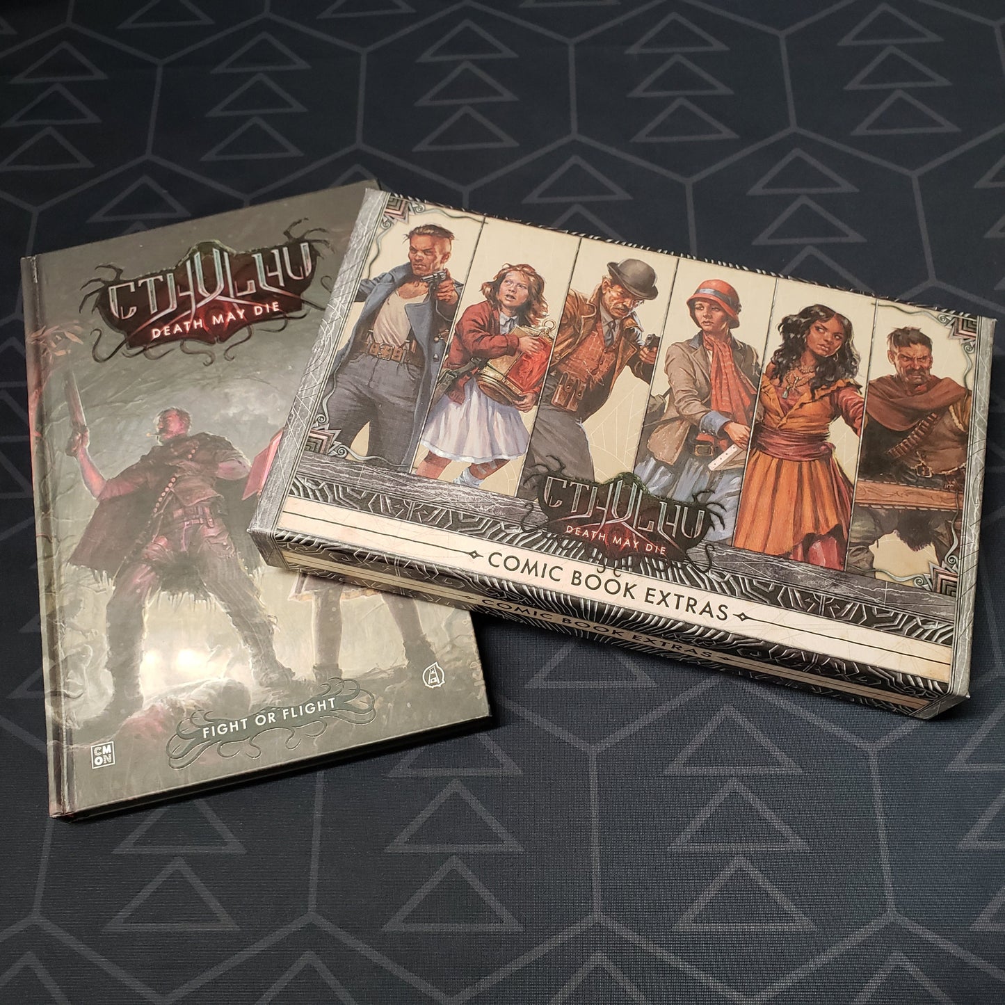 Image shows the front covers of the box for the Comic Book Extras Vol. 1 expansion for the board game Cthulhu: Death May Die, as well as the Fight or Flight graphic novel