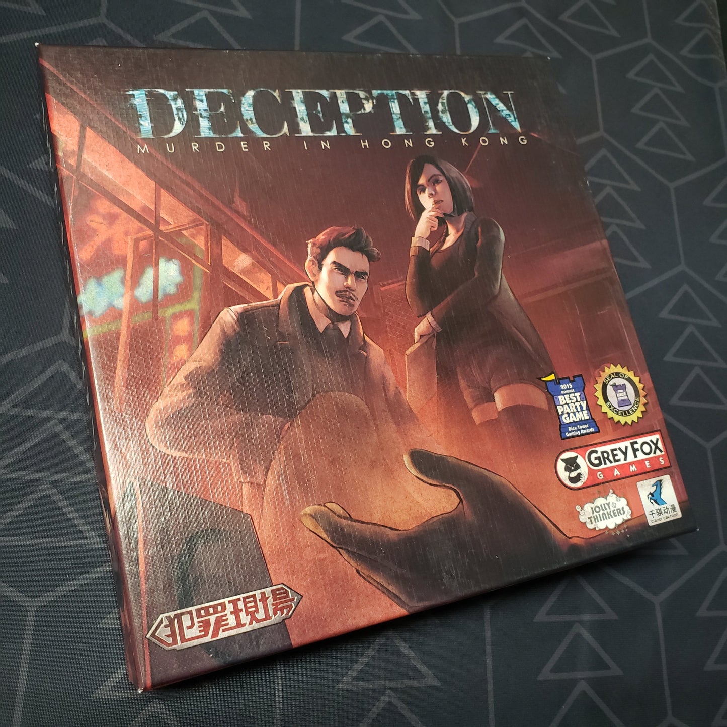 Image shows the front cover of the box of the board game Deception: Murder in Hong Kong