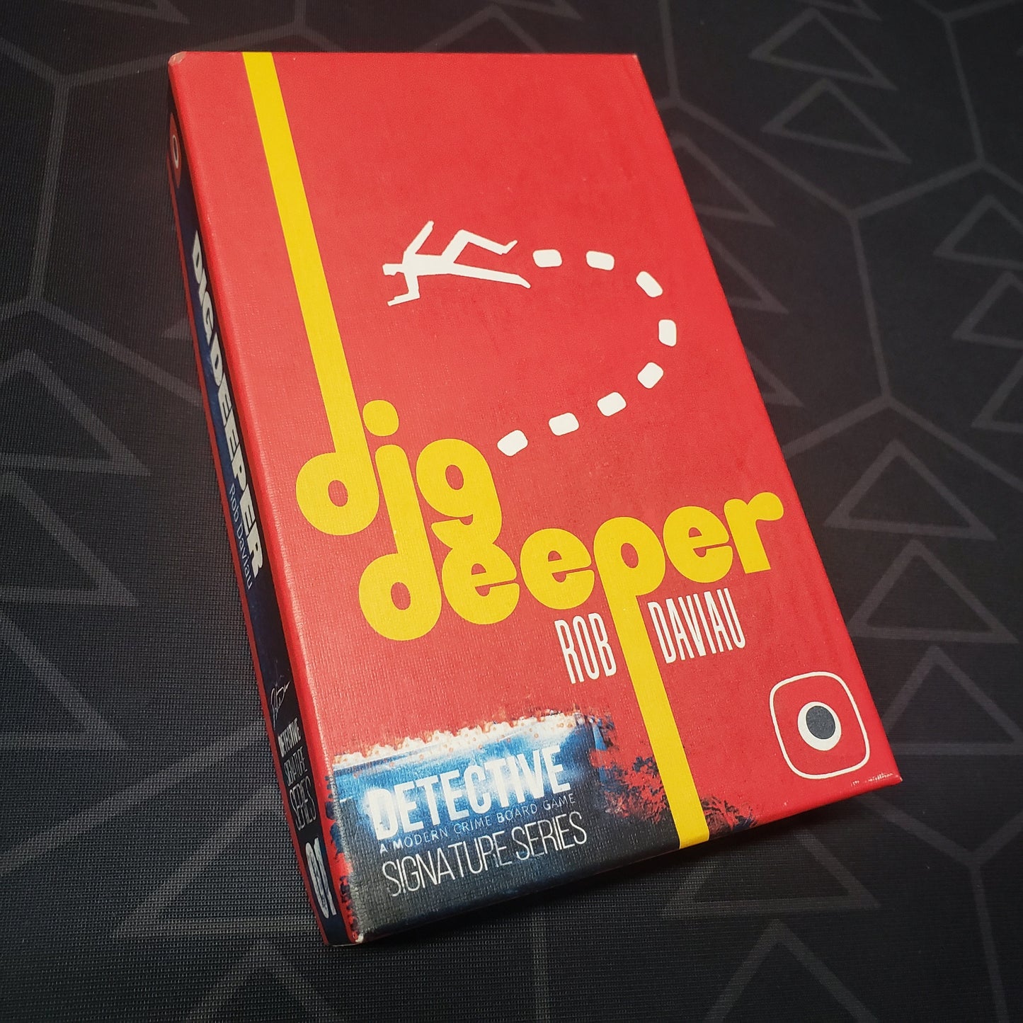Image shows the front cover of the box of the Signature Series: Dig Deeper expansion for the board game Detective