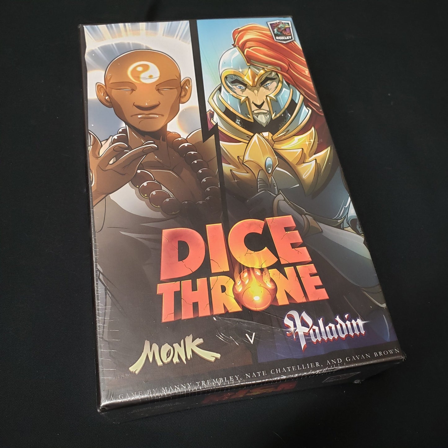 Image shows the front cover of the box of the board game Dice Throne: Monk v. Paladin