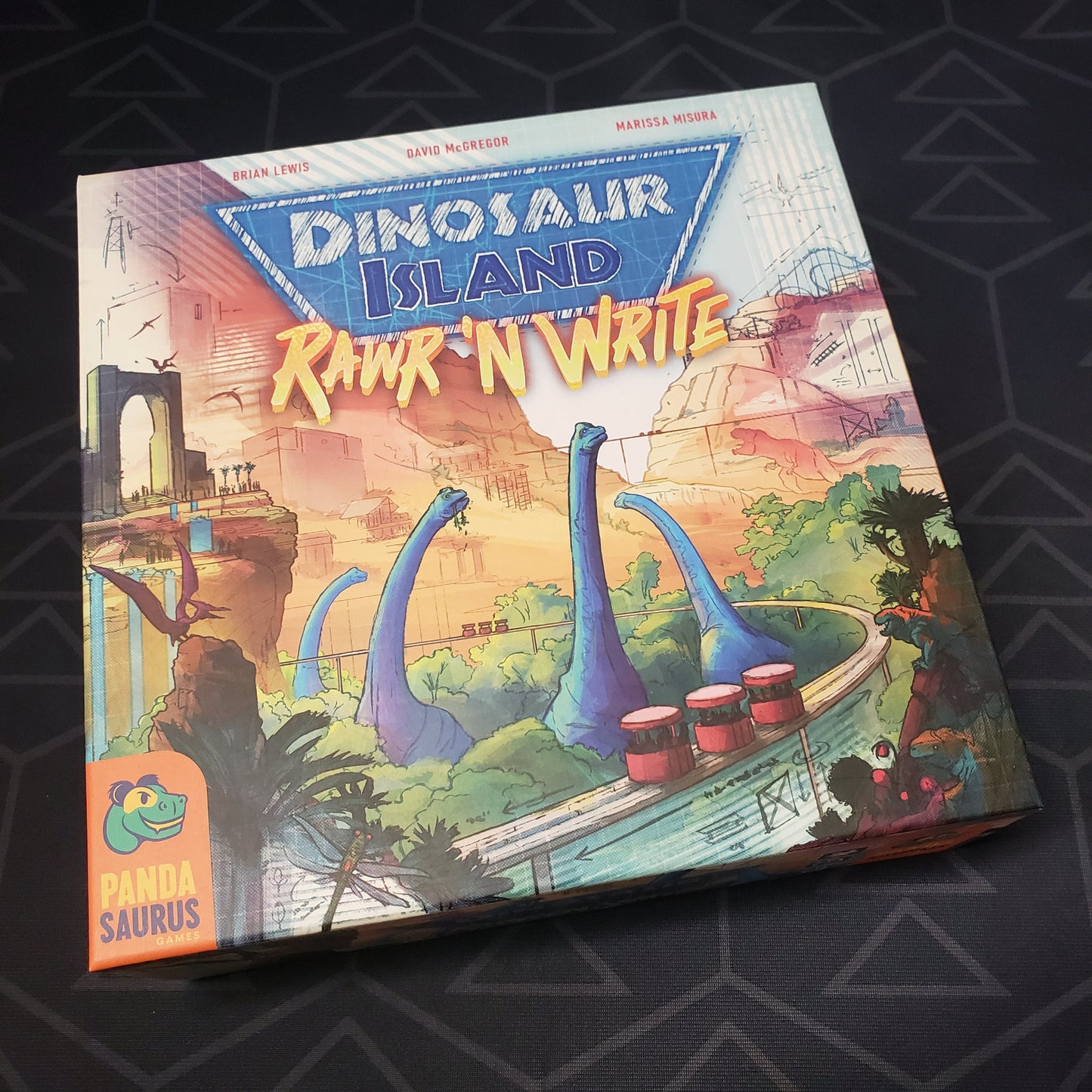 Image shows the front cover of the box of the Dinosaur Island: Rawr 'N Write board game