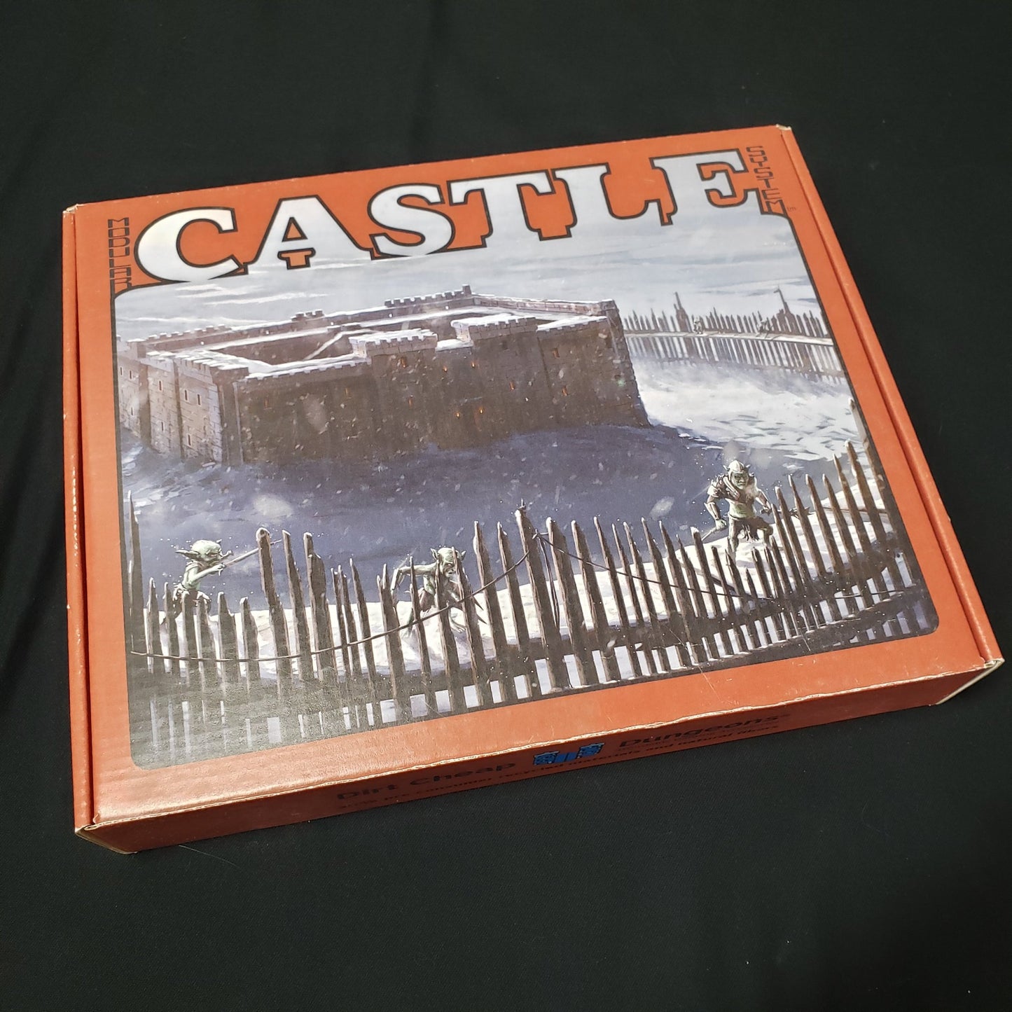 Image shows the front cover of the box of the Castle set for the Dirt Cheap Dungeons modular terrain system