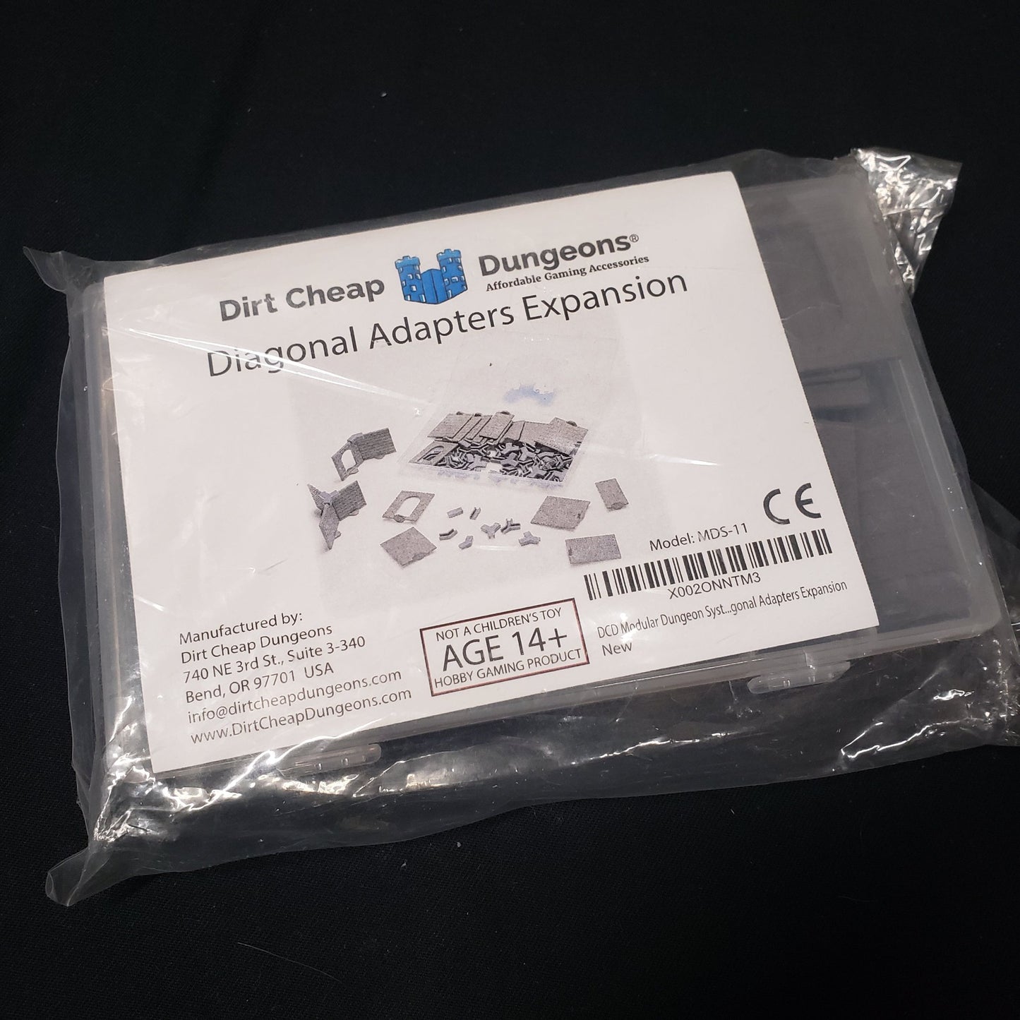 Image shows the front of the packaging of the Diagonal Adapters expansion set for the Dirt Cheap Dungeons modular terrain system