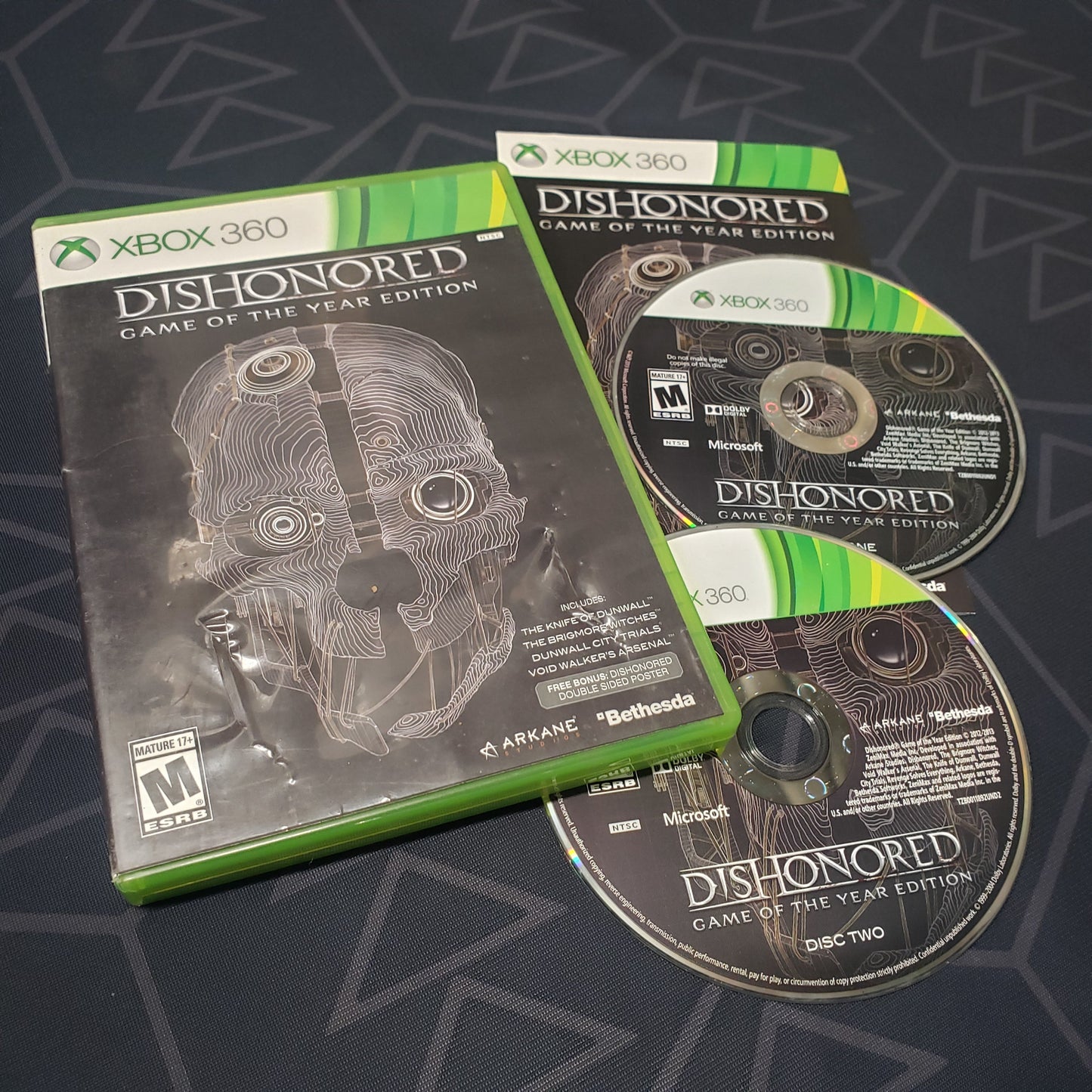 Image shows the case, manual and two discs for the video game Dishonored: Game of the Year Edition for Xbox 360