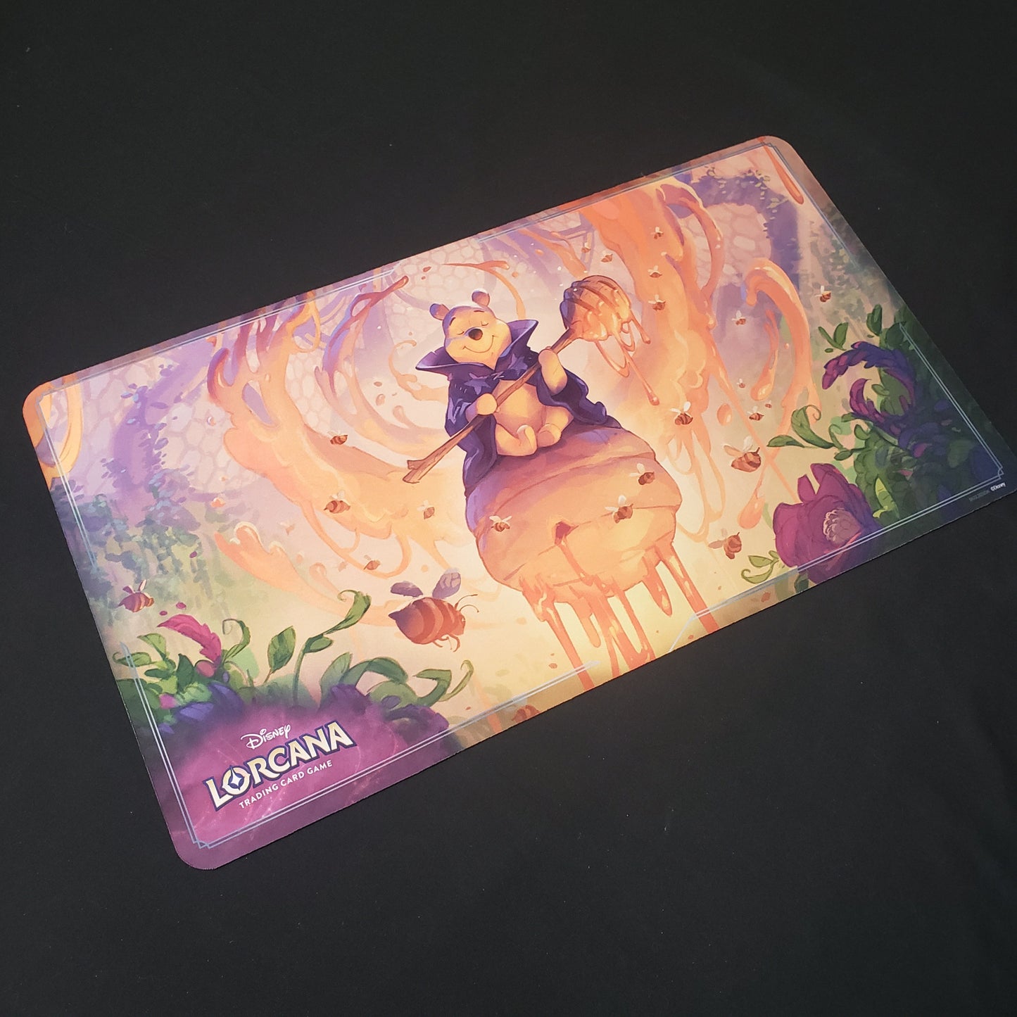 Image shows a playmat featuring Rise of the Floodborn: Winnie the Pooh, Hunny Wizard art for the Disney Lorcana card game