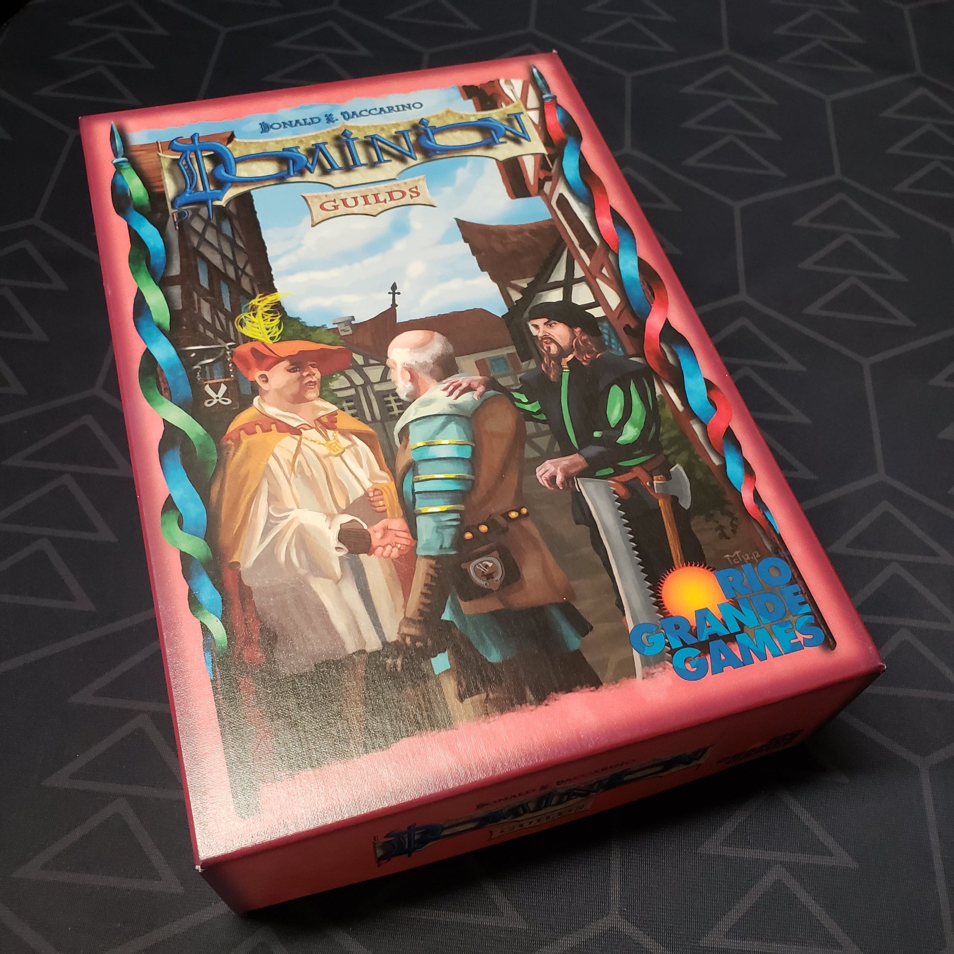 Image shows the front cover of the box of the Guilds expansion for the card game Dominion
