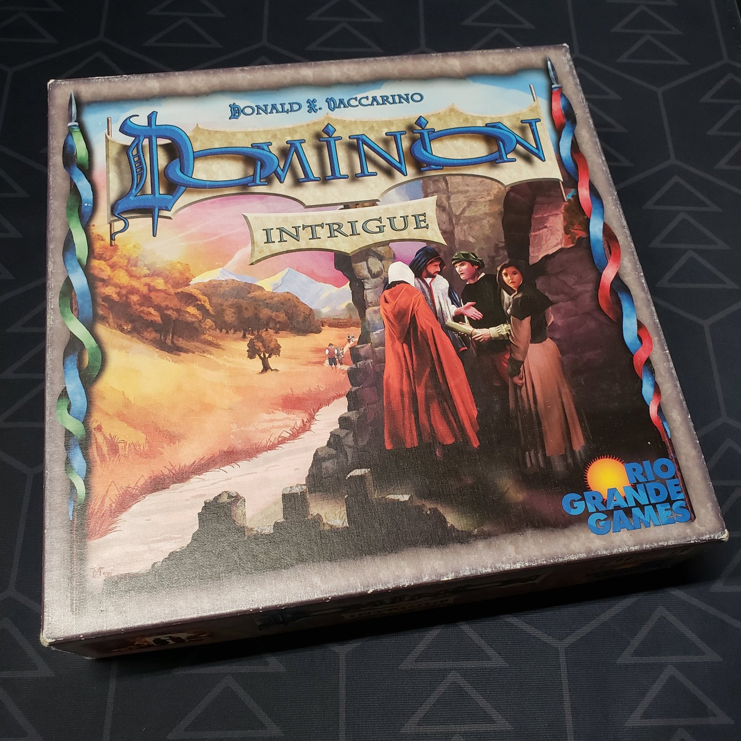 Image shows the front cover of the box for the Dominion: Intrigue card game