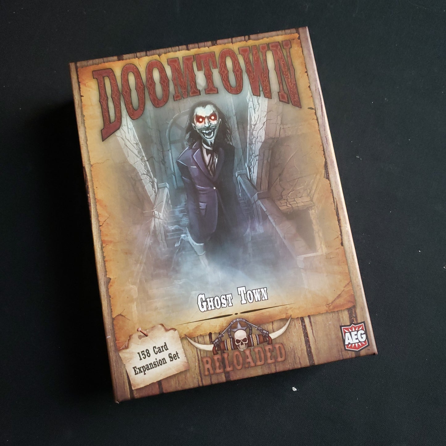 Image shows the front cover of the box of the Ghost Town expansion for the card game Doomtown: Reloaded