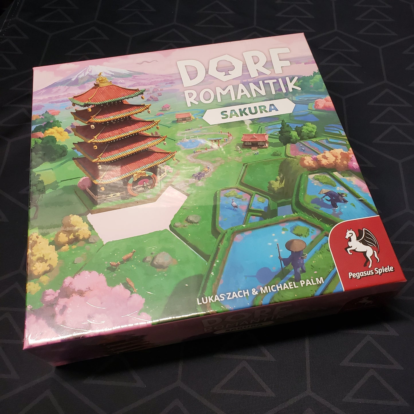 Image shows the front cover of the box of the Dorfromantik: Sakura board game