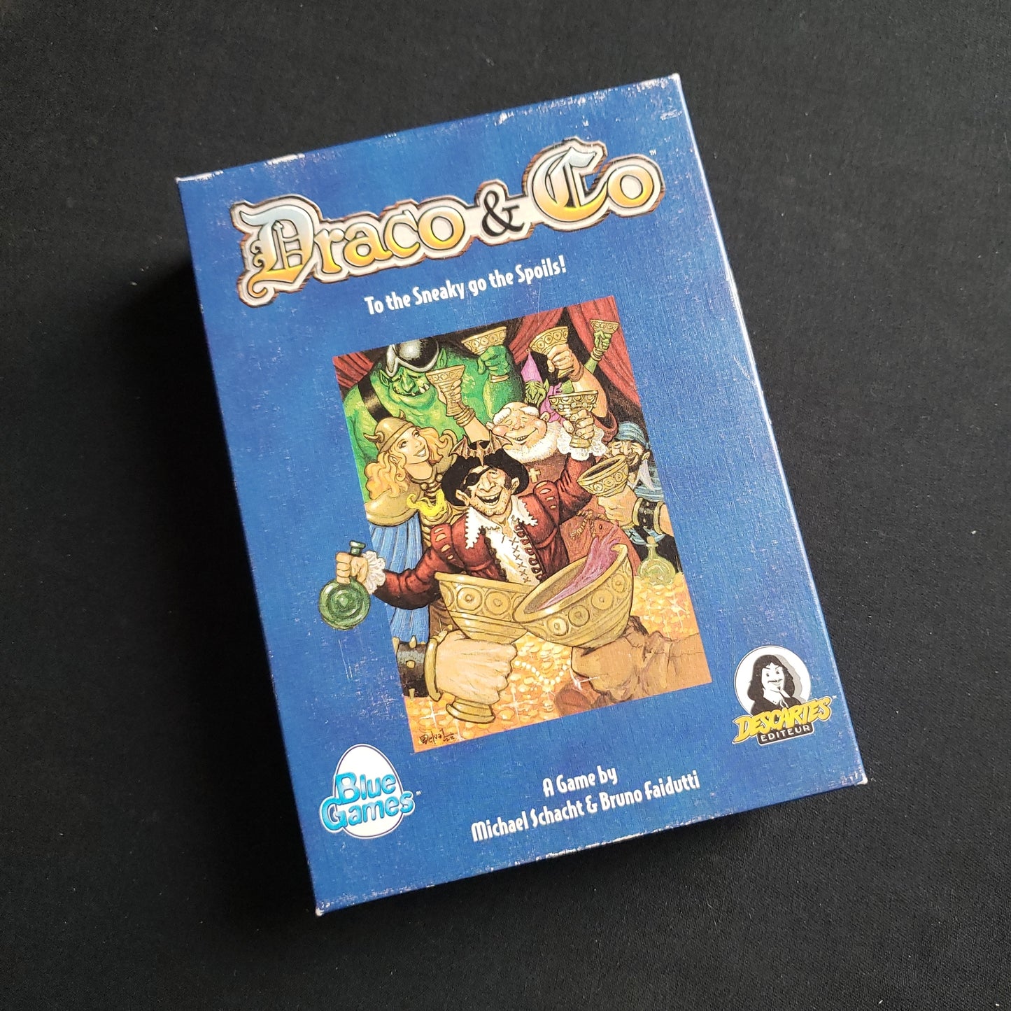 Image shows the front cover of the box of the Draco & Co card game