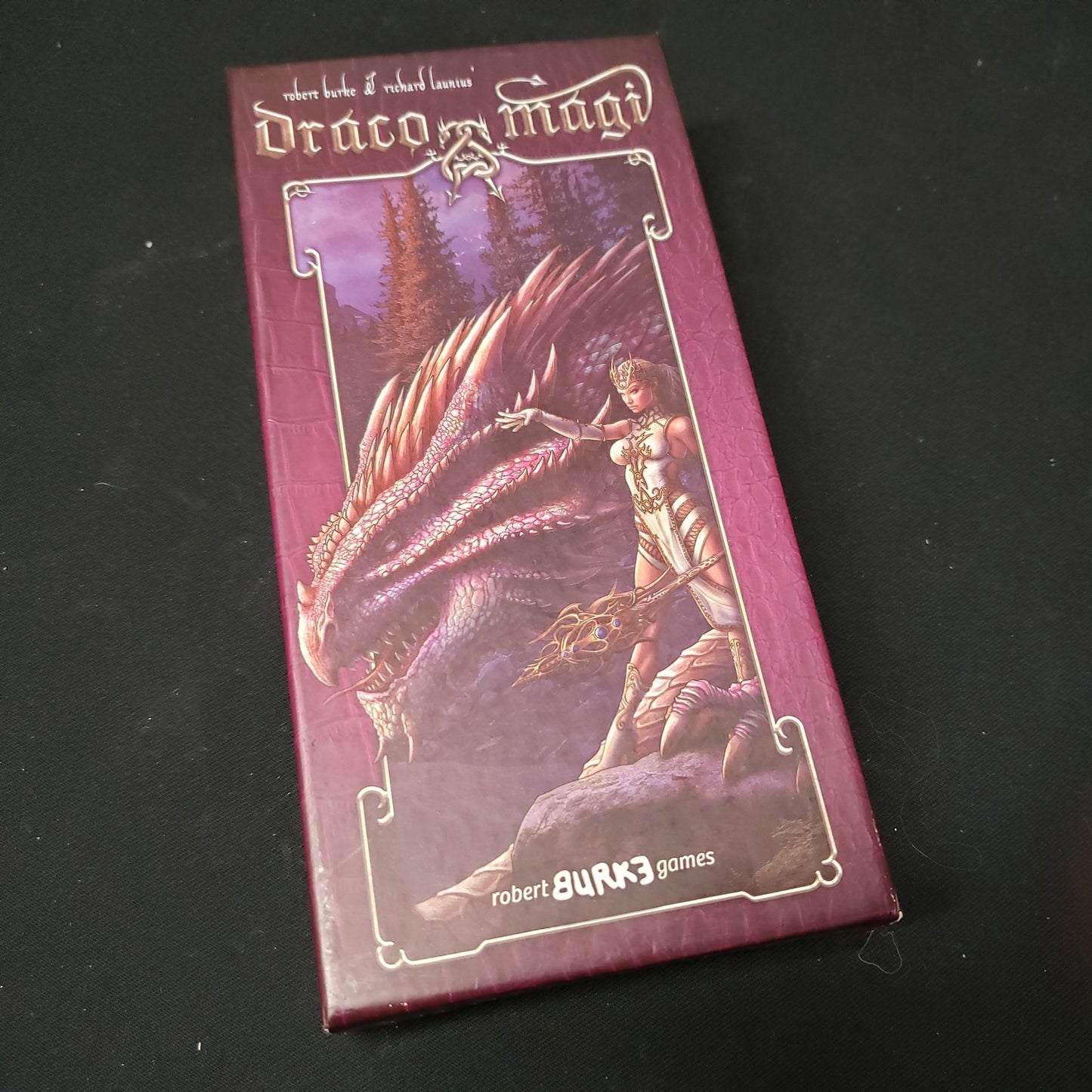 Image shows the front cover of the box of the Draco Magi card game