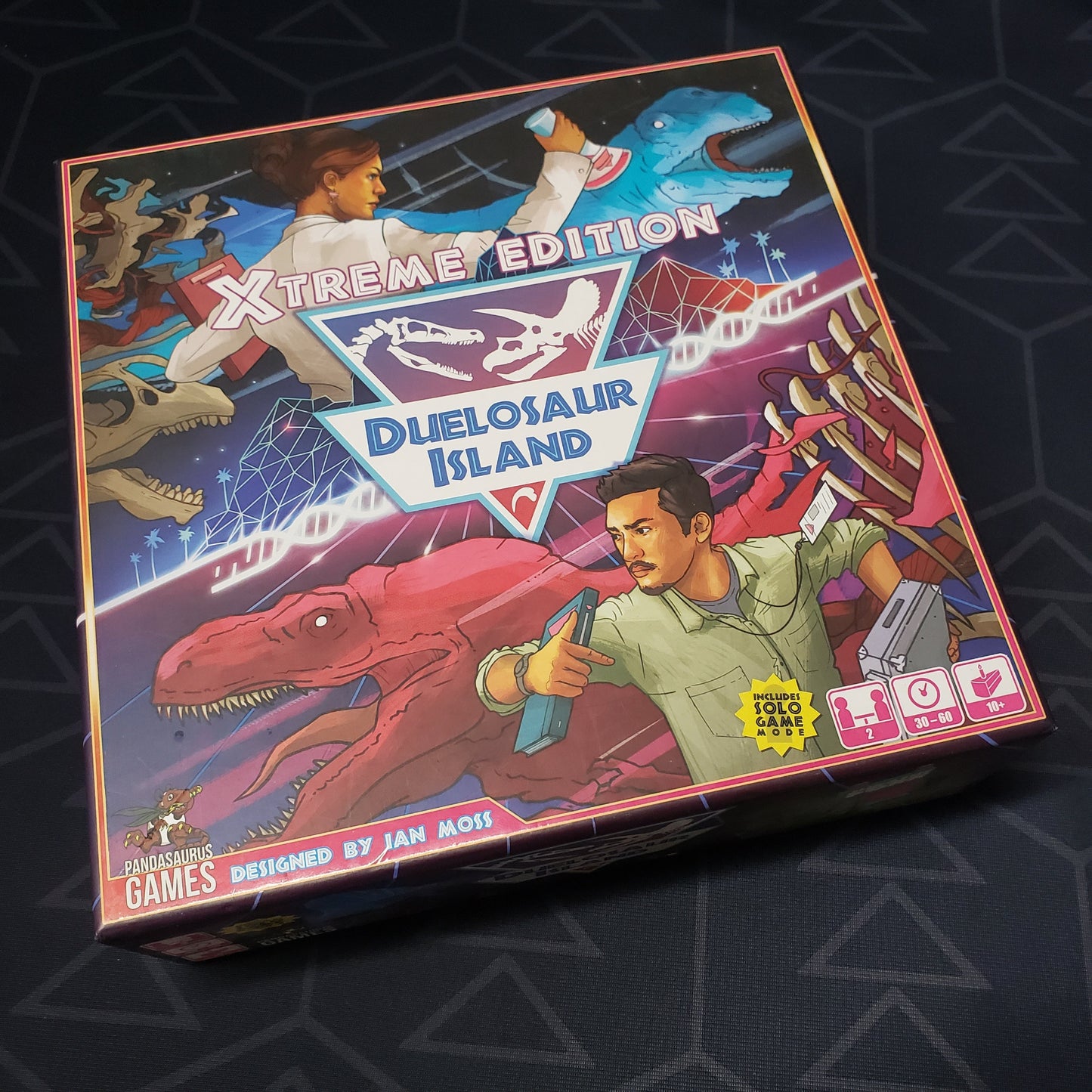 Image shows the front cover of the box of the Xtreme Edition of the board game Duelosaur Island
