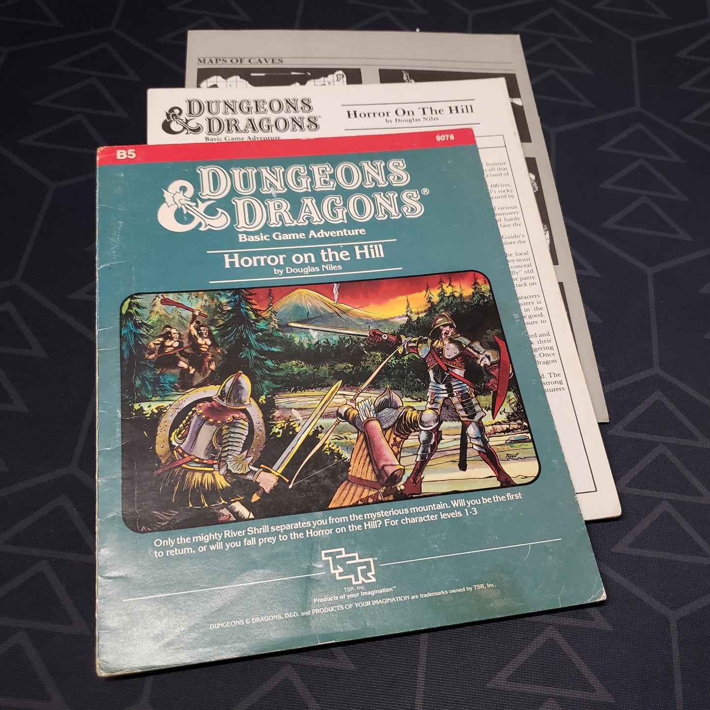 Image shows the front cover of the folio for the Horror on the Hill adventure module for the roleplaying game Dungeons & Dragons: First Edition, with the booklet and map inserts fanned out